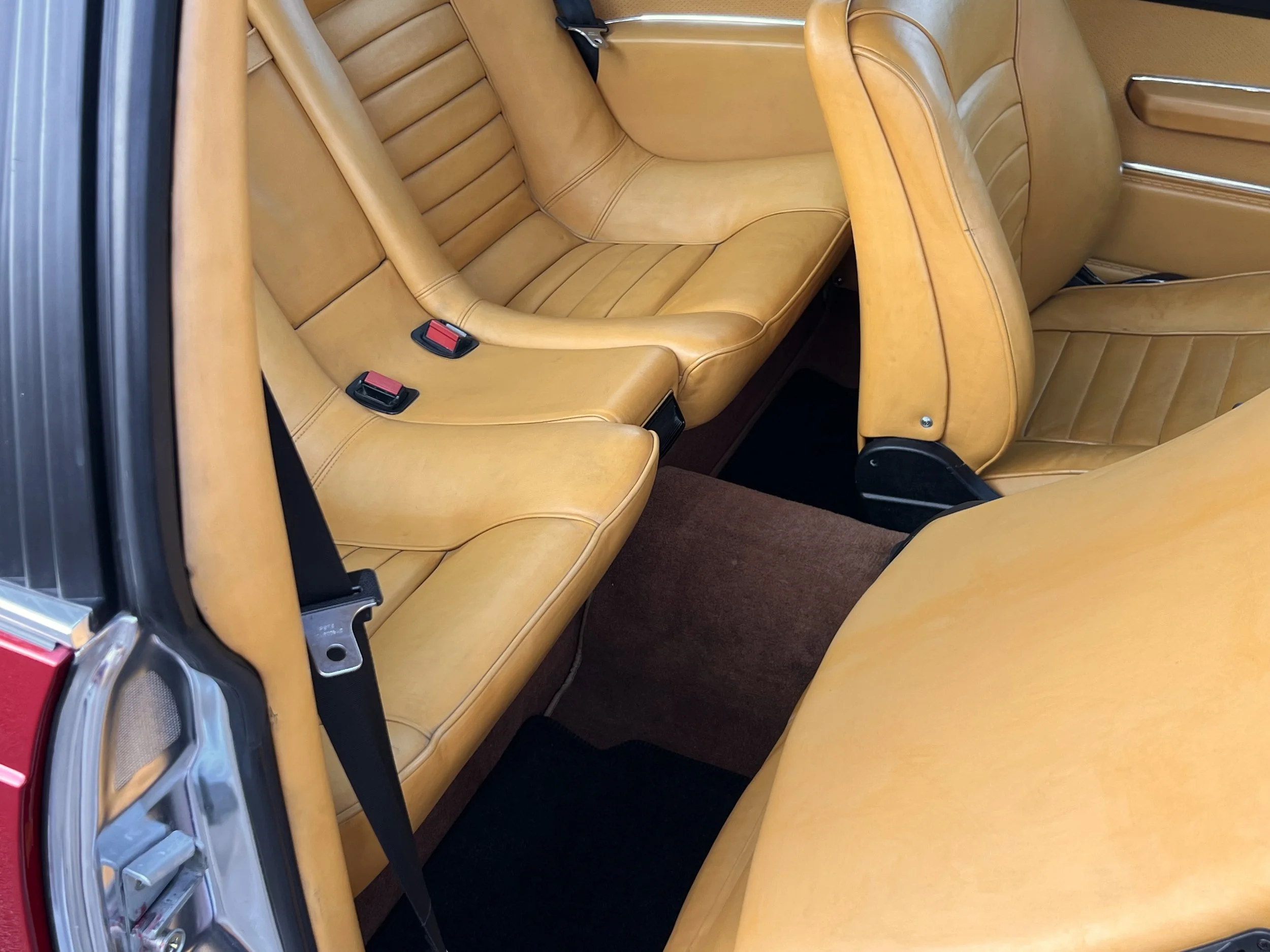 The interior of a vintage 1977 BMW 630 csi car showing tan leather seats and brown carpeting.