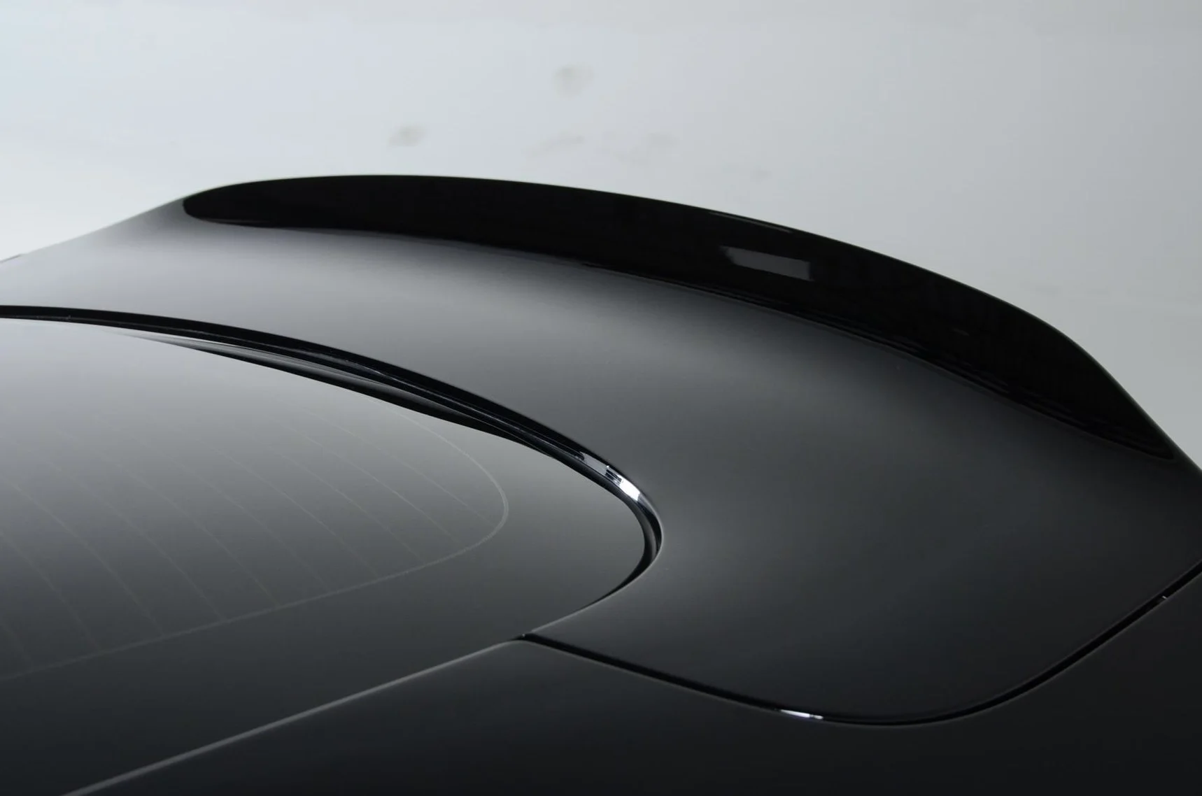Close-up of a sleek, black electric or modern car with a smooth, shiny surface and a panoramic glass roof.