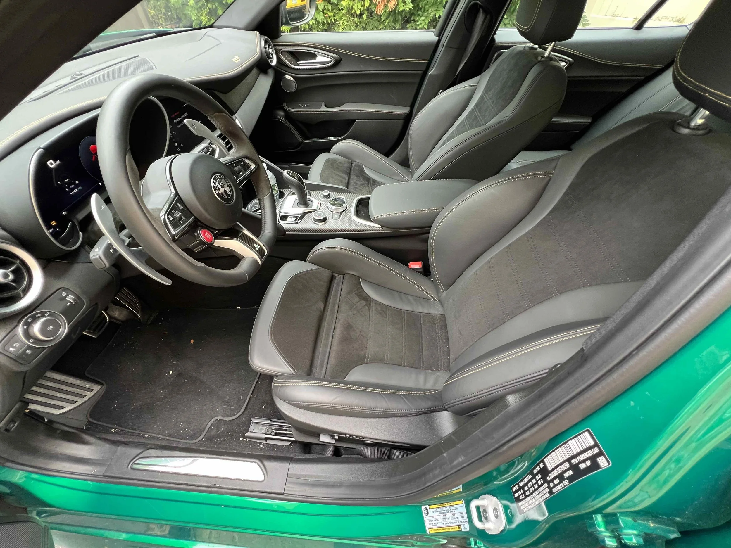 The interior of a green sports car showing black and gray leather seats, steering wheel, and dashboard with controls.