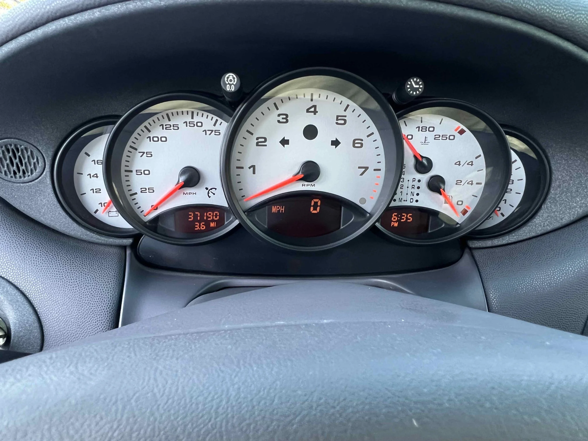 Car dashboard displaying speedometer, tachometer, fuel gauge, temperature gauge, odometer, and clock.