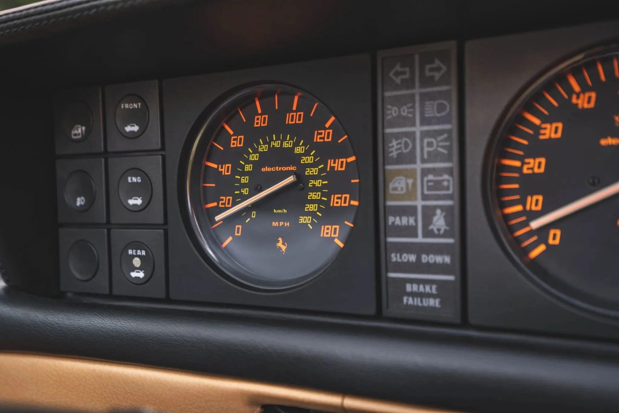 Close-up of a car dashboard with speedometer, tachometer, and various indicator lights.