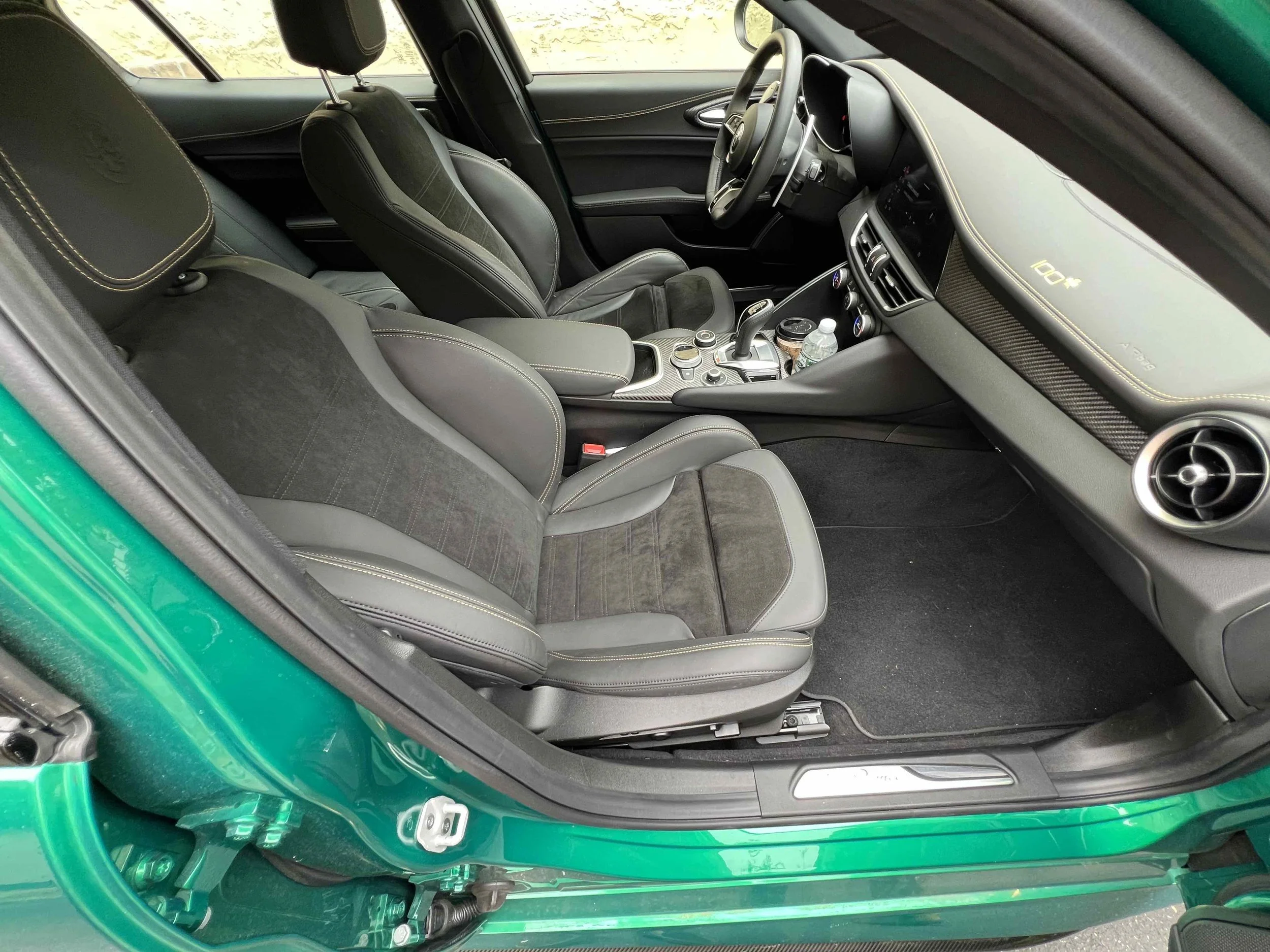 Interior of a modern sports car showing black leather and fabric seats, a center console with gear shifter, and dashboard with infotainment screen.
