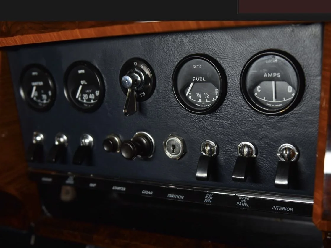 Dashboard with gauges and switches, including fuel and amperage gauges.