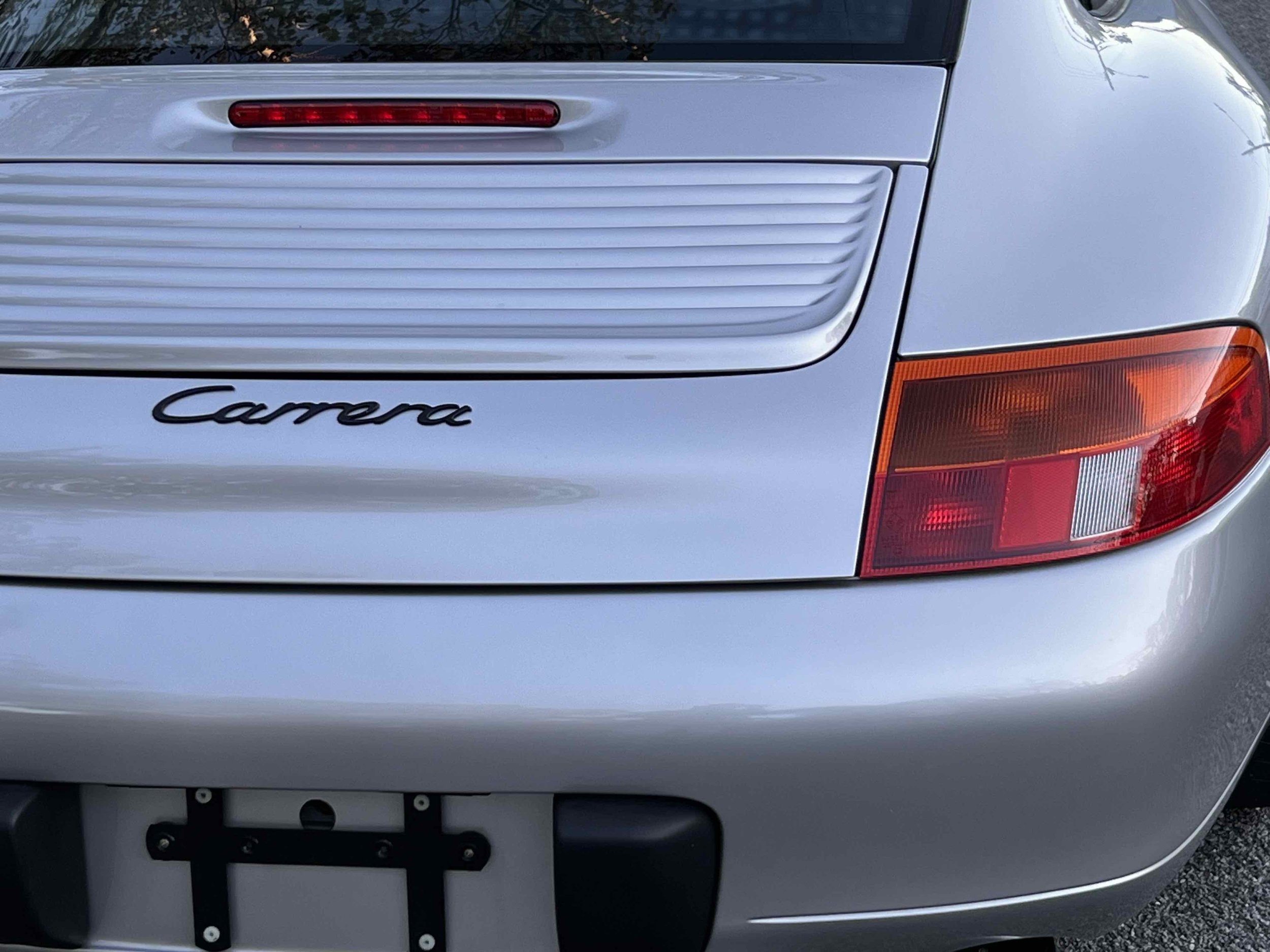 Rear view of a silver Porsche Carrera with tail lights and a rear badge visible.