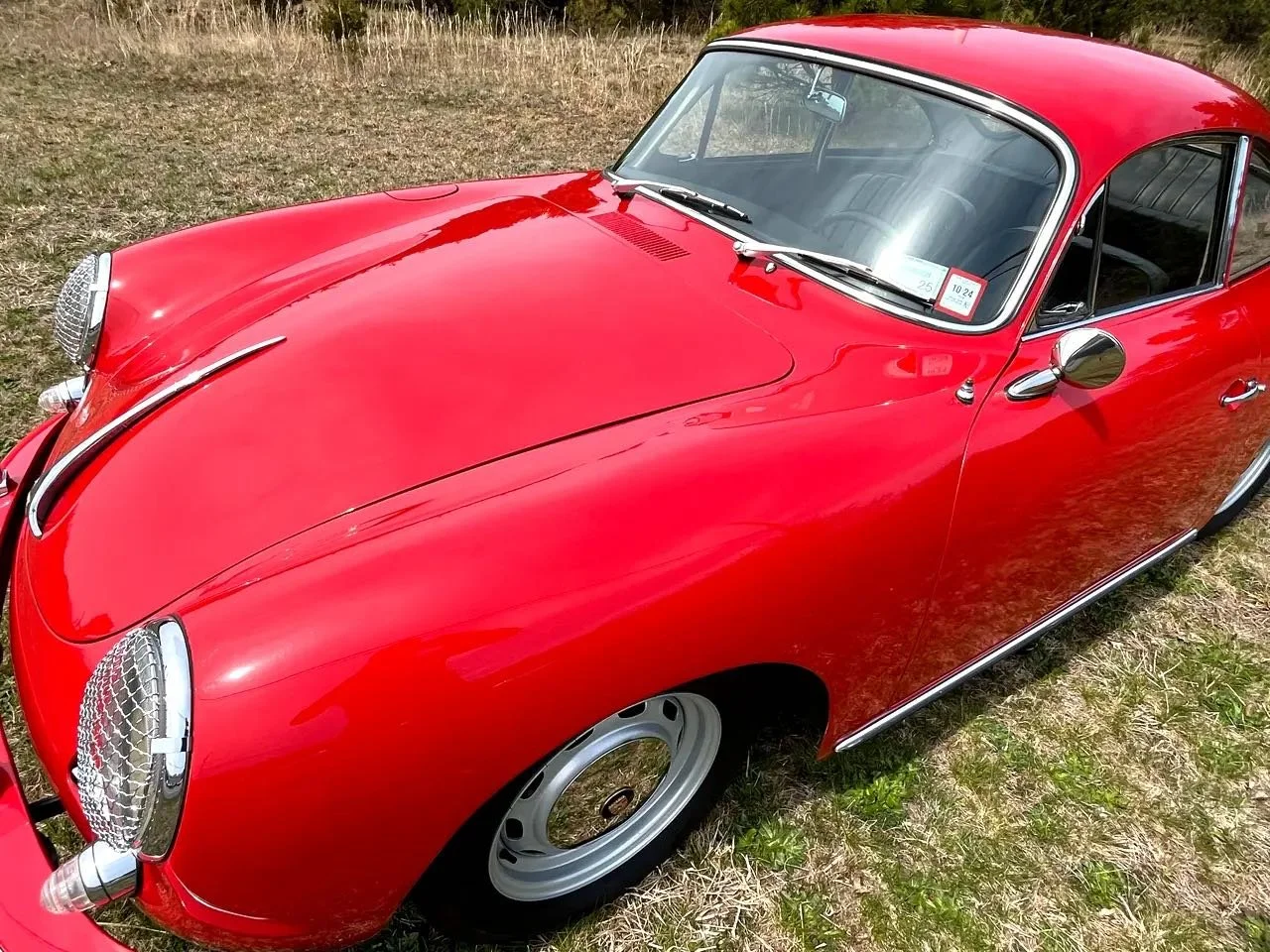 Red vintage sports car parked on grass outdoors.