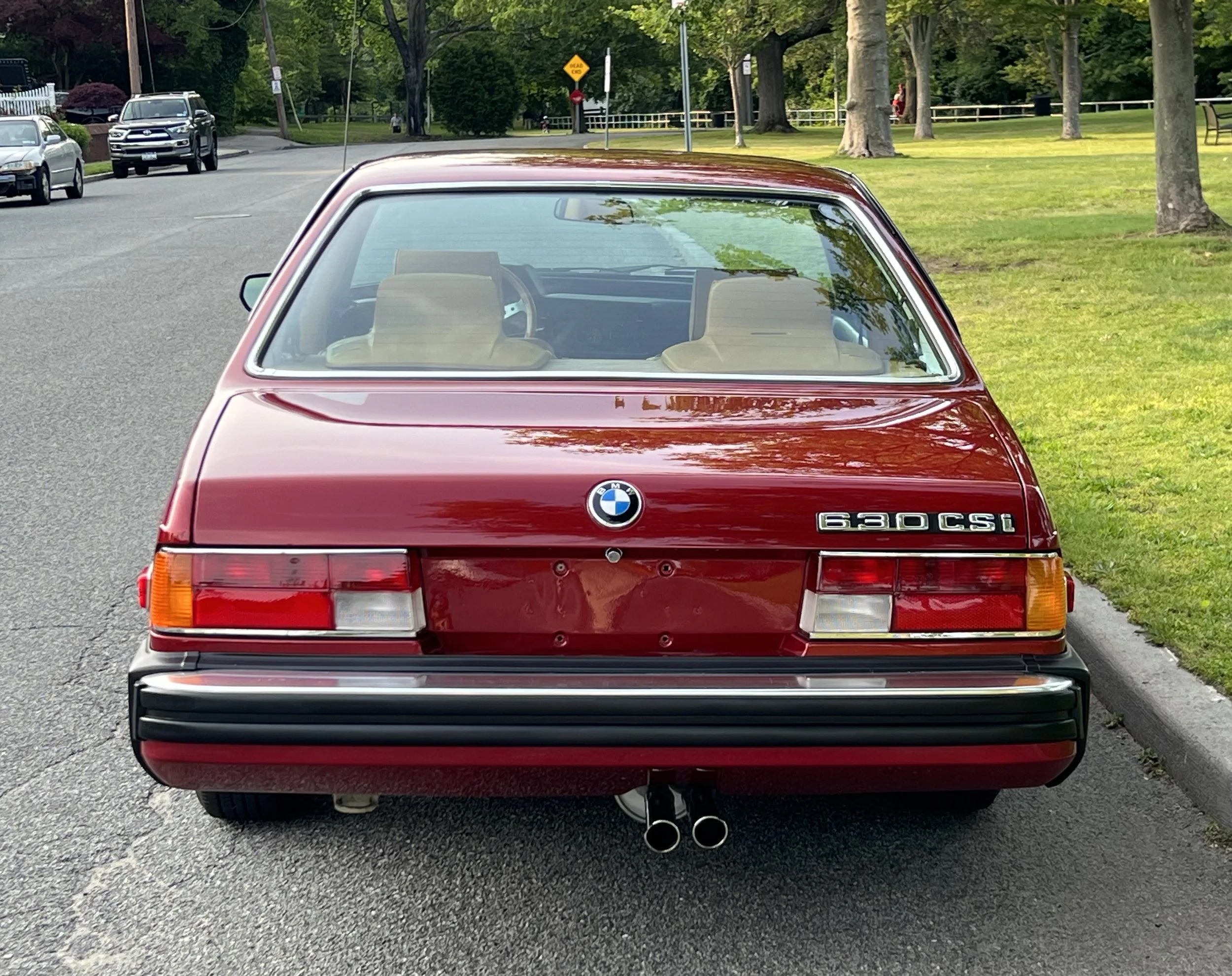 Back of Ruby Red 1977 BMW 630 csi on display in park for sale at FlowHaus