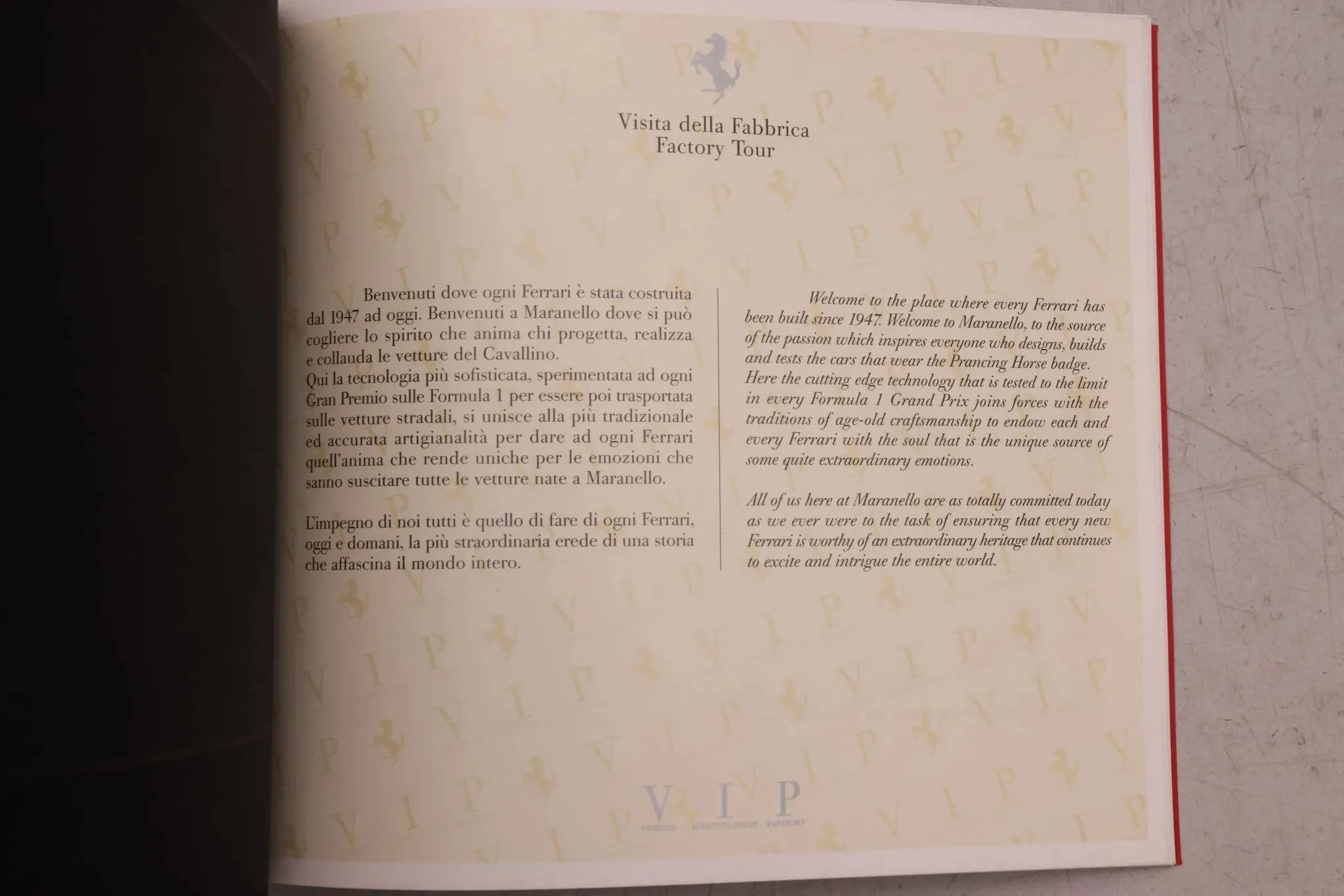 Open booklet with Italian and English text about Ferrari factory tour, featuring a gold Ferrari logo at the top center and a VIP logo at the bottom center.