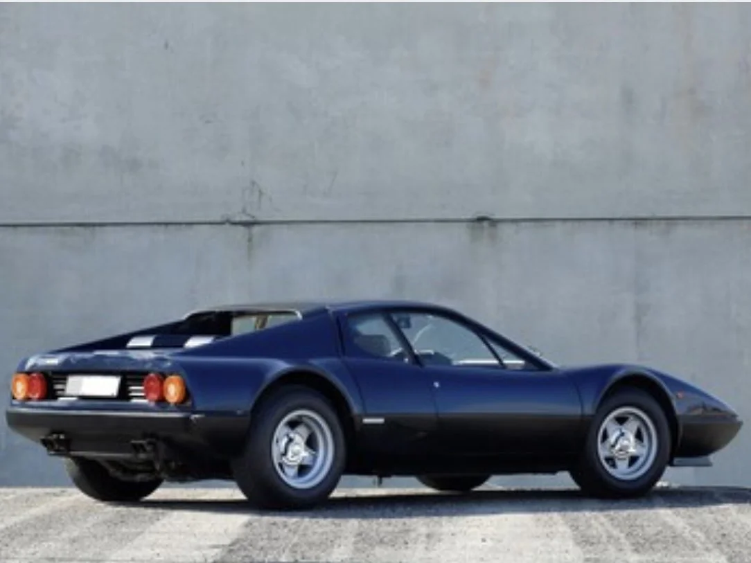Blue 1979 Ferrari 512 BB on display in front of concrete wall
