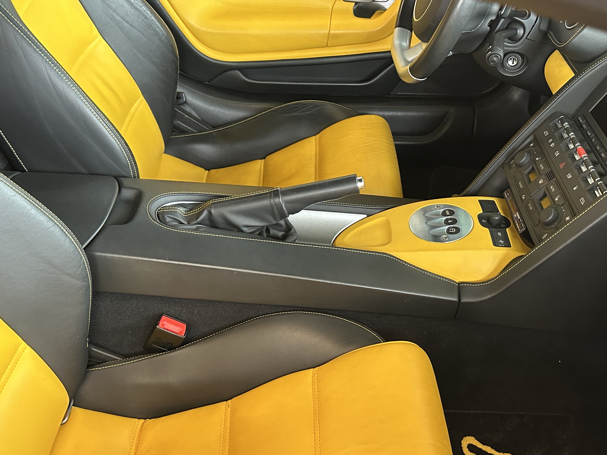 Interior of a car with a black and yellow color scheme, yellow seats, and a center console with various controls and a gear shift.