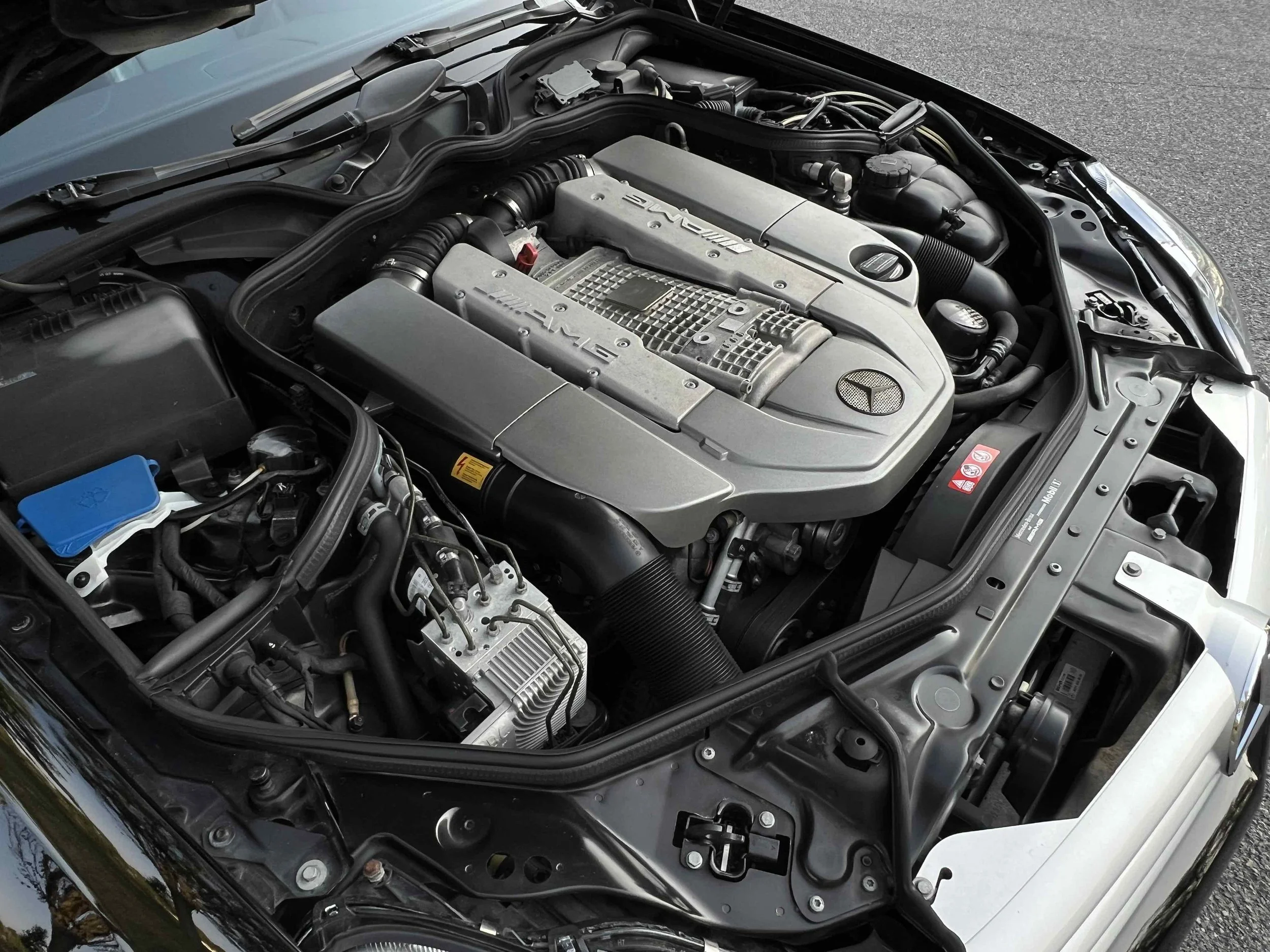 Under the hood of a Mercedes-Benz car, showcasing the engine and various components.