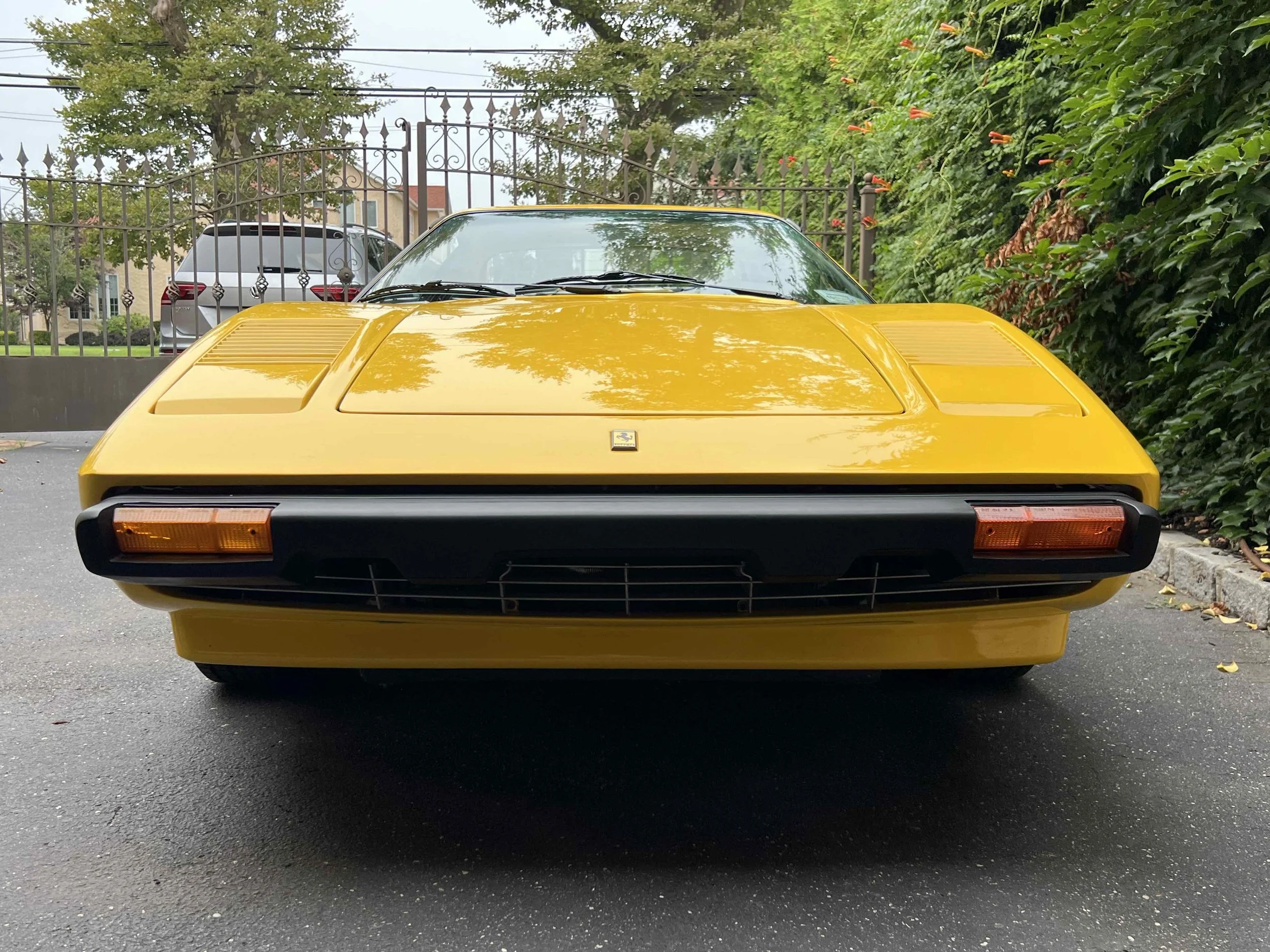 Front view of a yellow Ferrari sports car parked on a driveway.