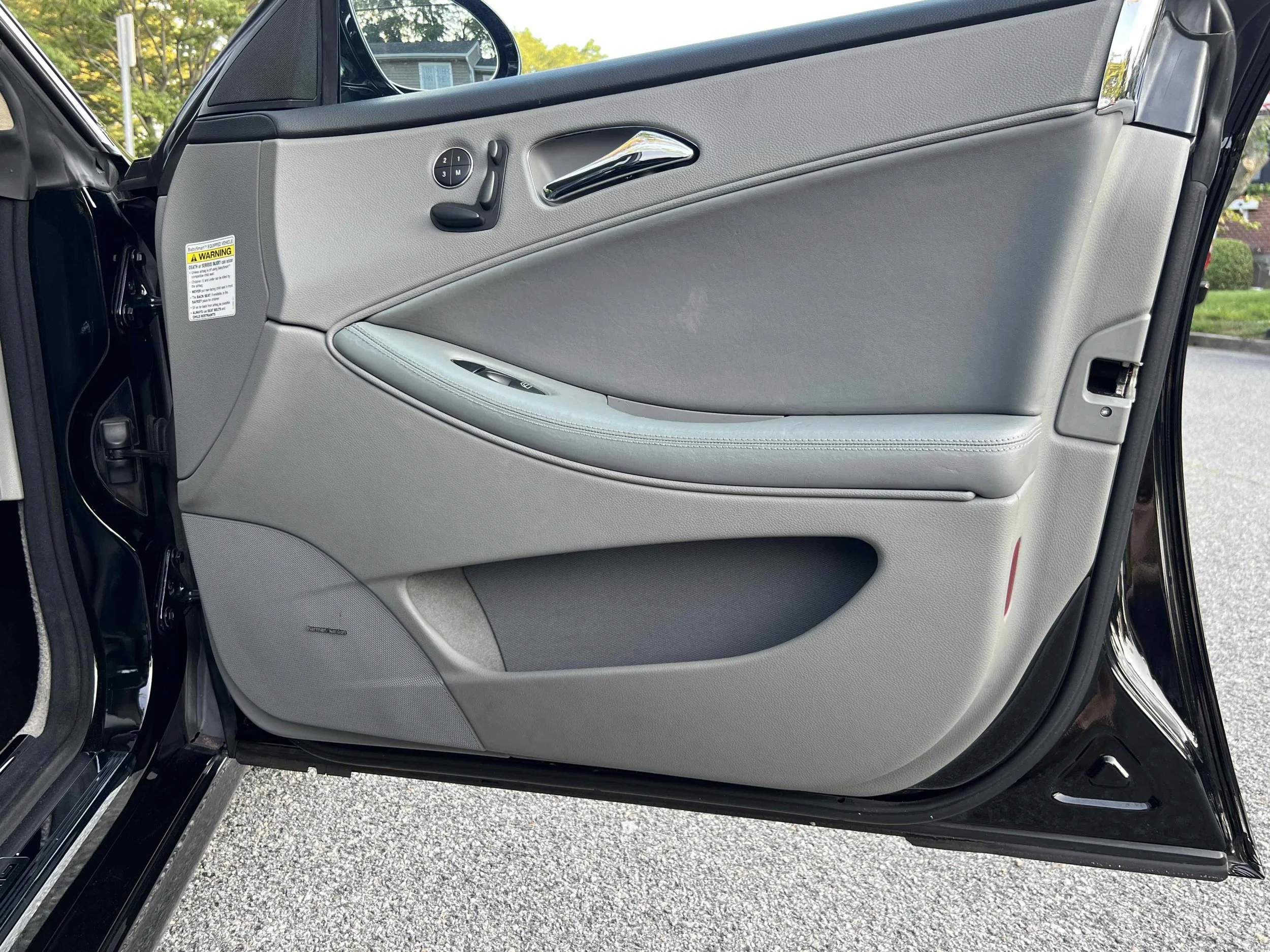 Close-up of a car door interior with light gray panel and window controls.