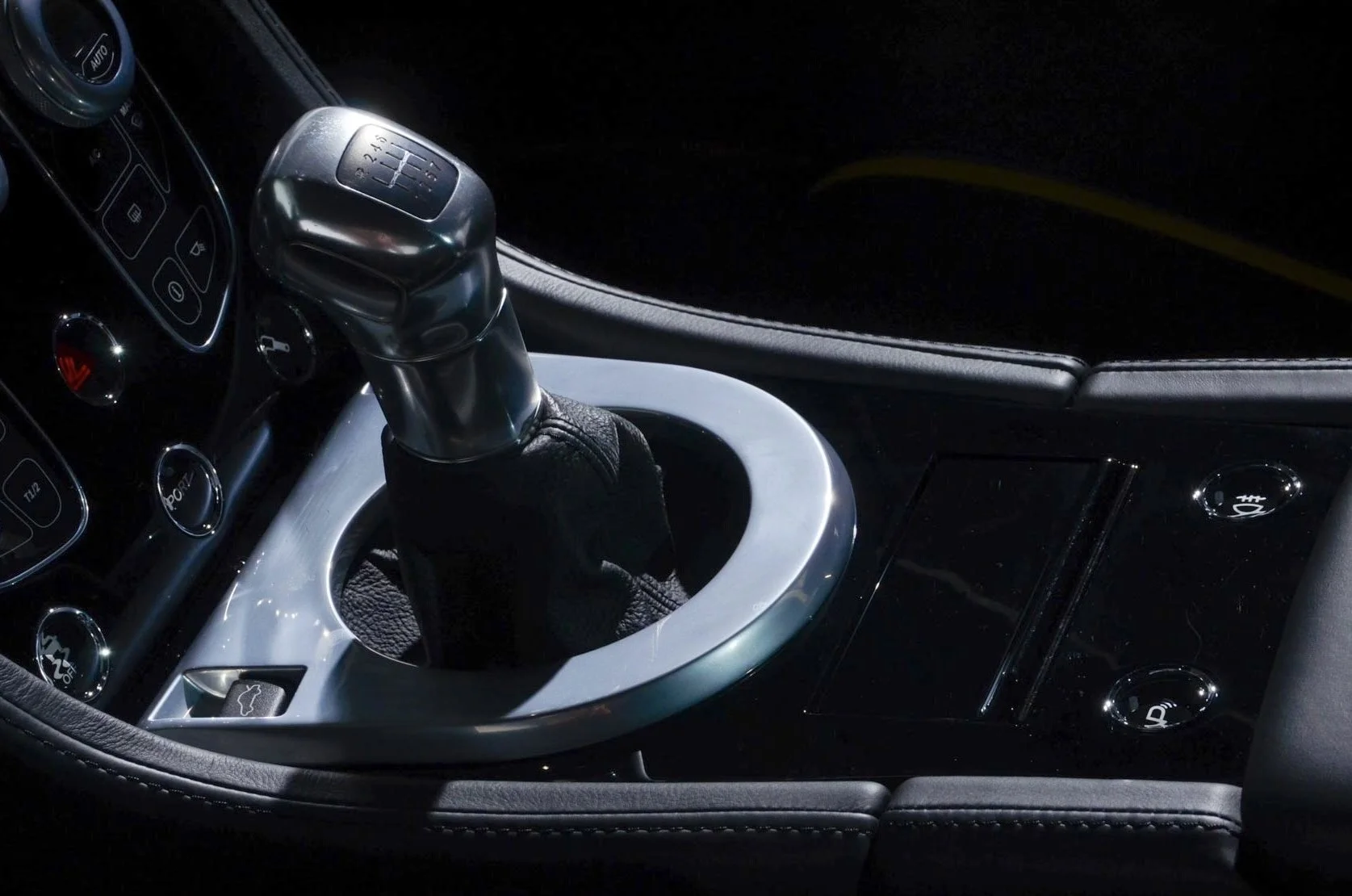 Close-up of a car's gear shift lever and center console with various buttons and controls.