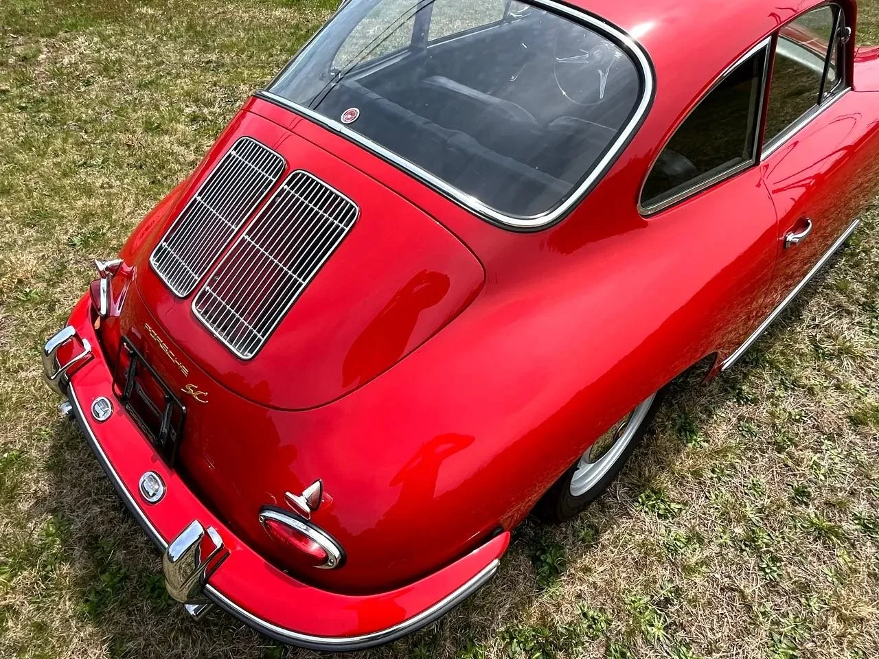 Top view of a vintage red Porsche 356 with a rear engine grille on grass.