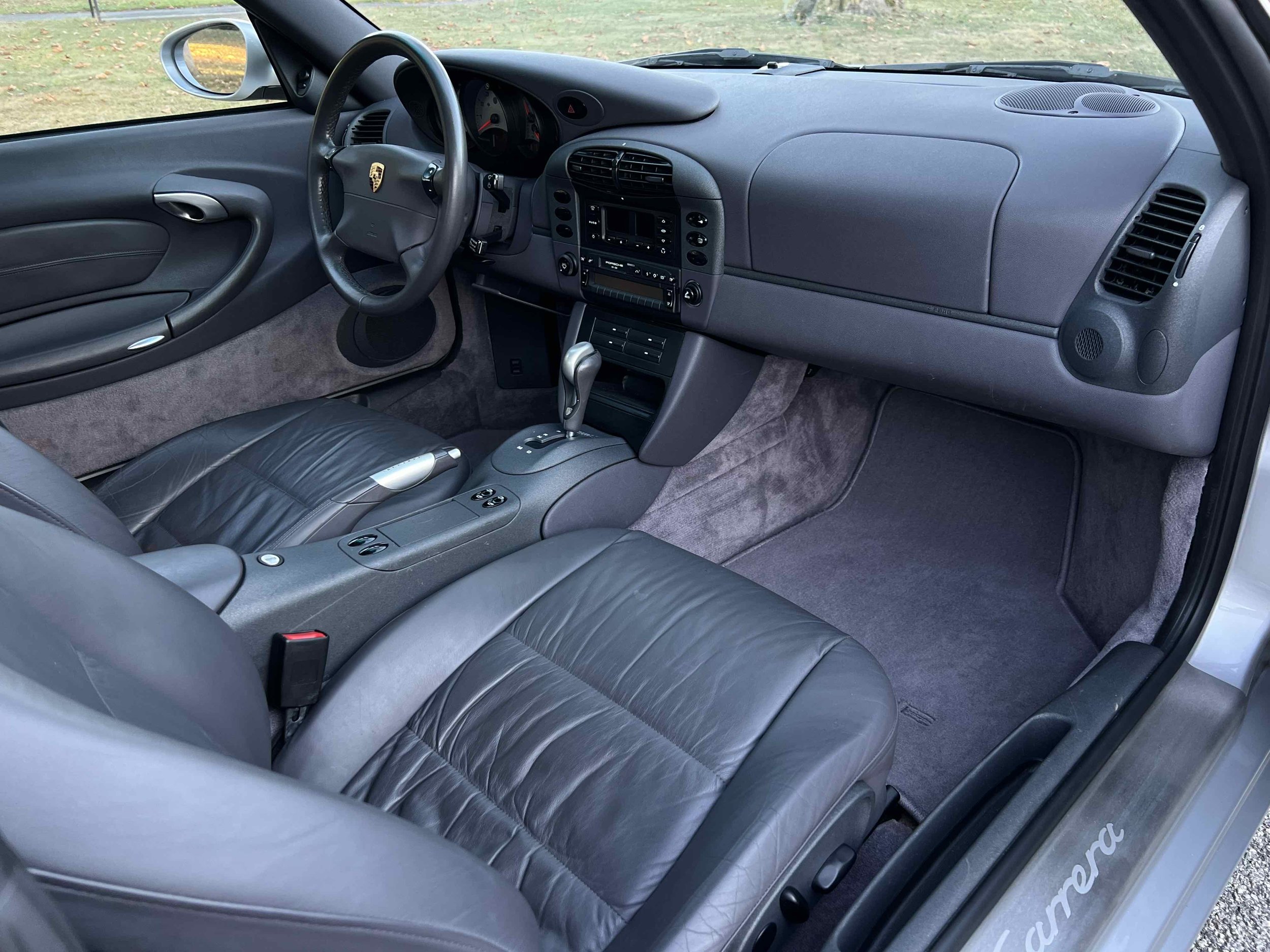 Interior of a Porsche Carrera showcasing leather seats, a dashboard with an analog speedometer, and a center console with an automatic gear shift.