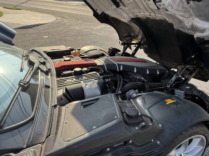 View of a car engine with the hood open, showing various engine components including the air intake and engine cover.
