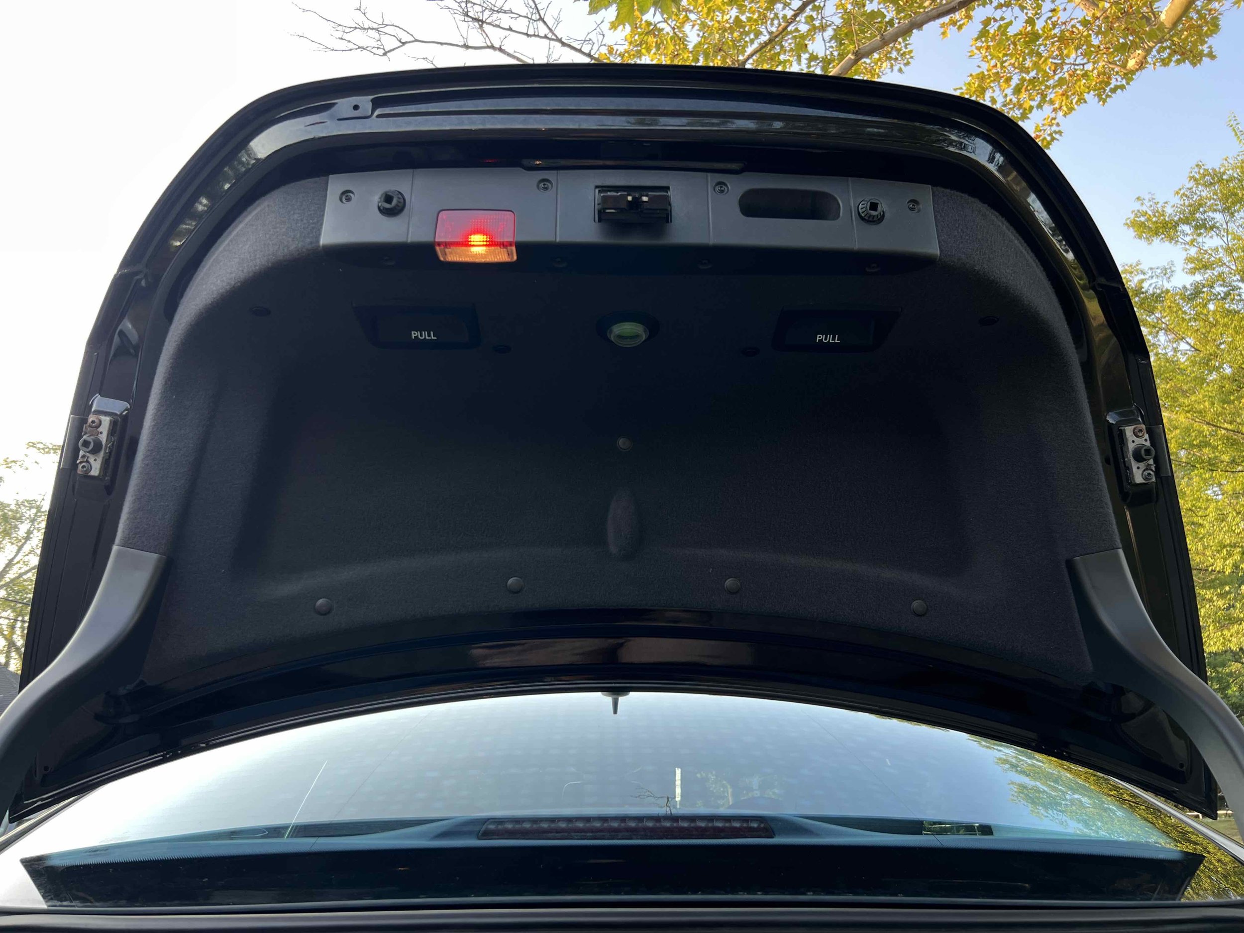 The open trunk of a car showing the interior lining and a red warning light at the top of the trunk lid.