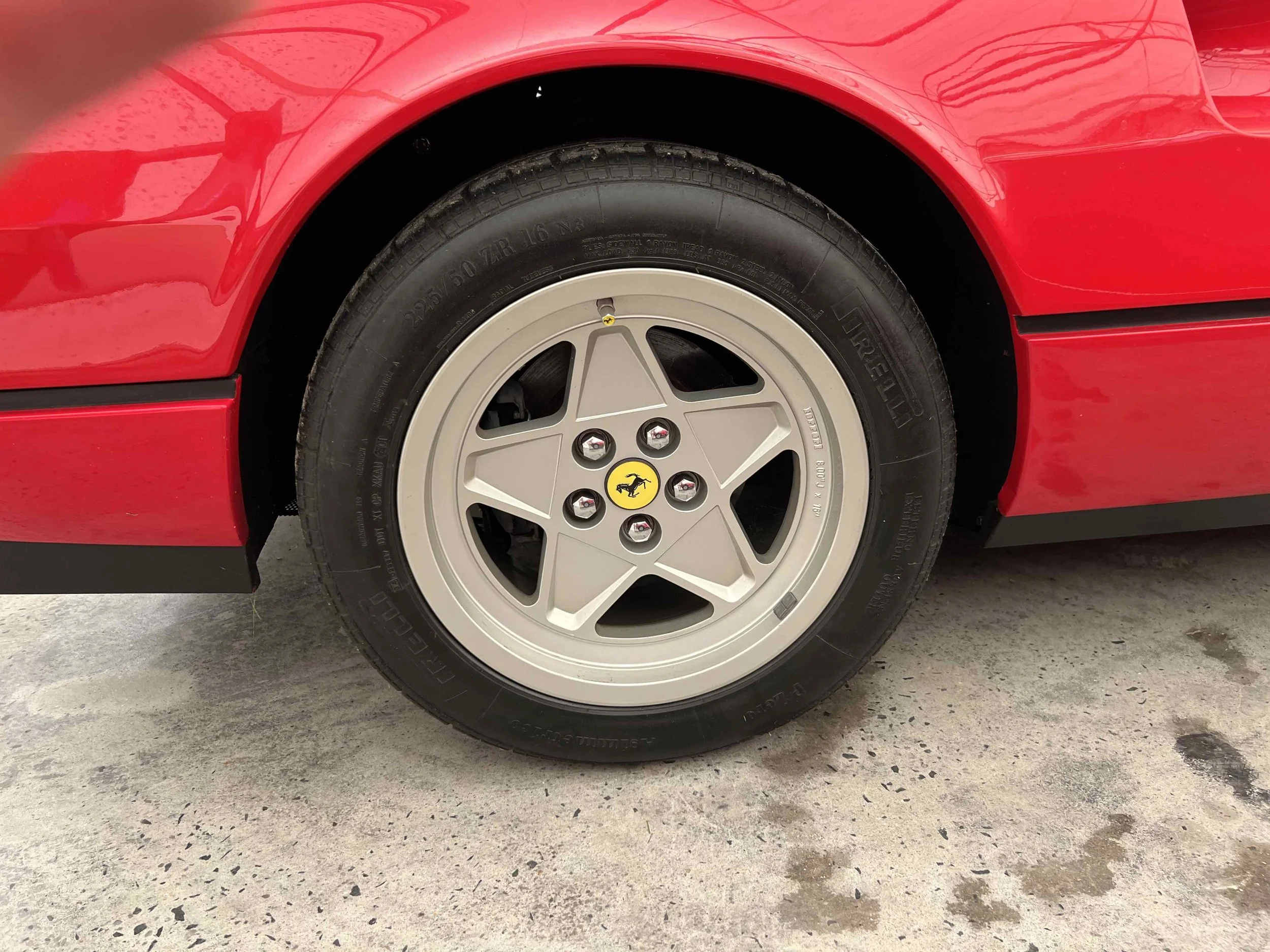Close-up of a red sports car tire and wheel with the Ferrari emblem in the center.