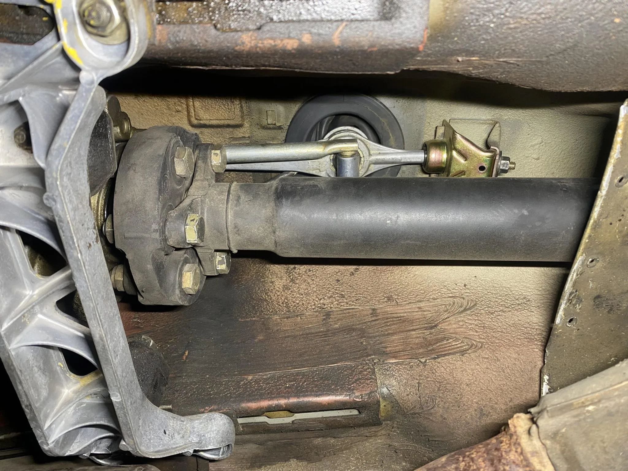 Close-up view of a mechanical drive shaft connected to a differential, mounted on a metal frame beneath a vehicle.