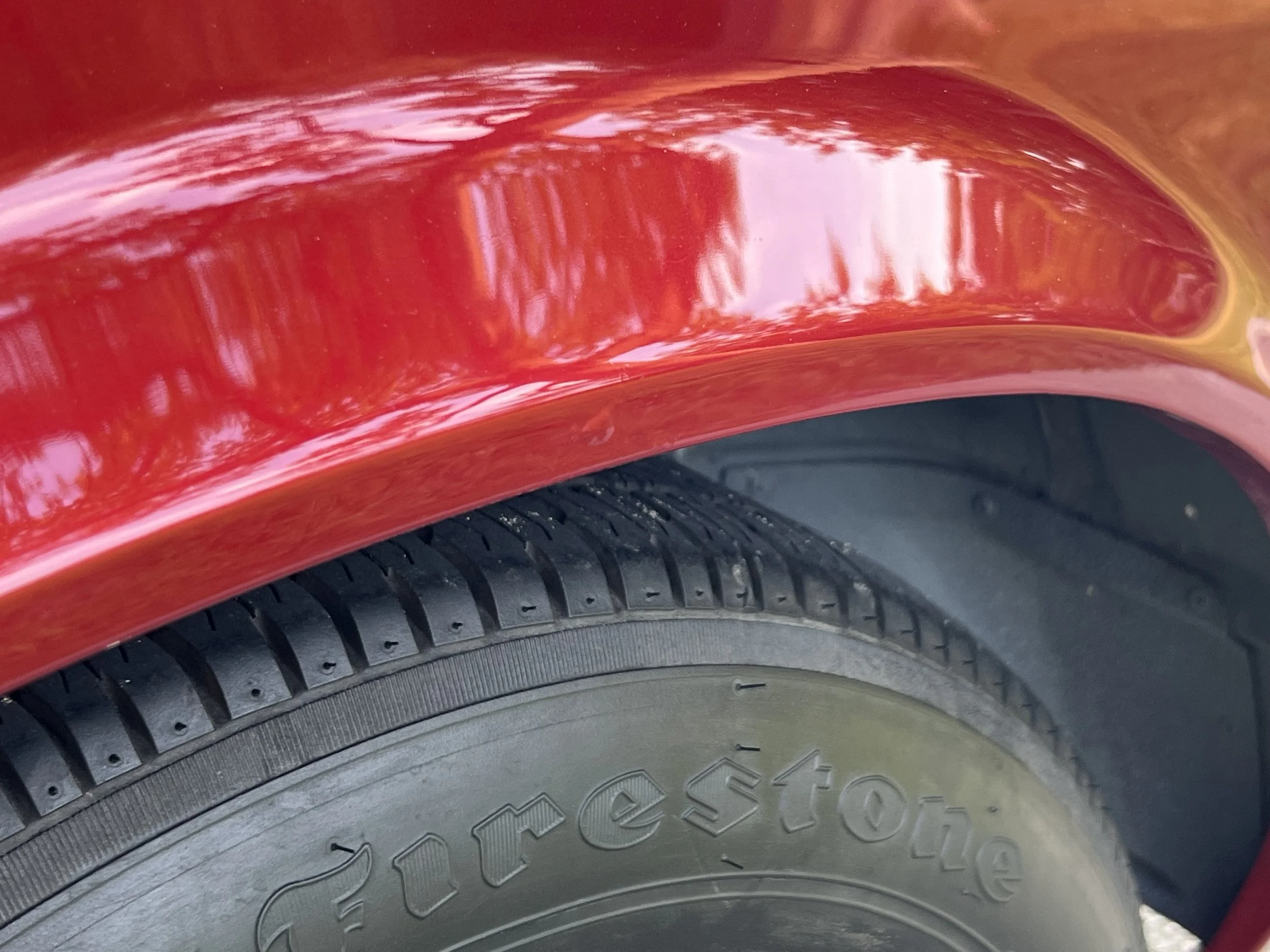 Close-up of a red BMW 630 csi wheel well with a black Bridgestone tire.