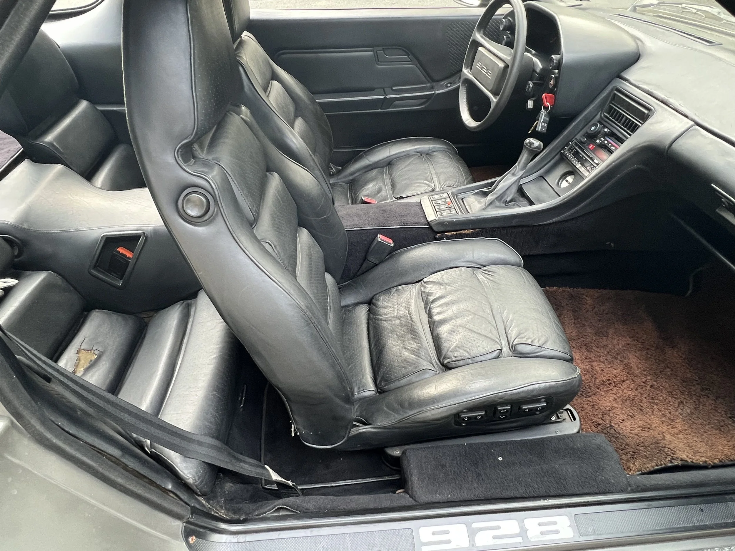 Interior of a car showing black leather seats, dashboard, steering wheel, and gear shift.