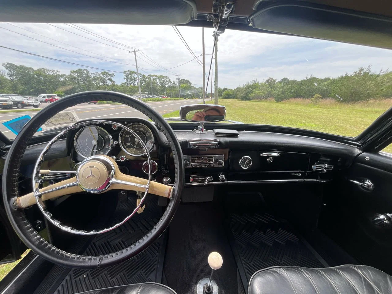 Interior of a vintage Mercedes-Benz car with a black dashboard, steering wheel, and gauges.