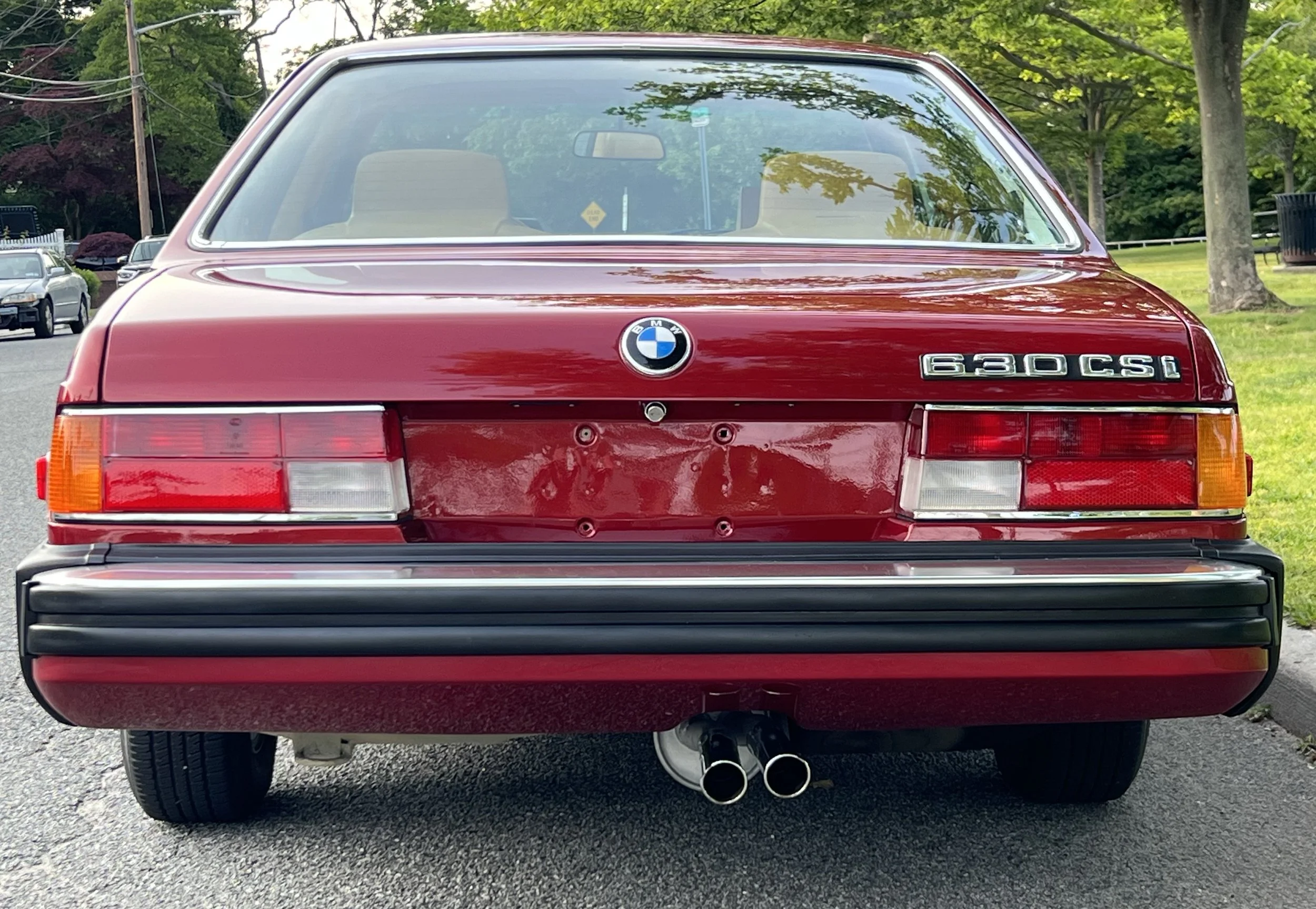 Back of Ruby Red 1977 BMW 630 csi on display in park for sale at FlowHaus