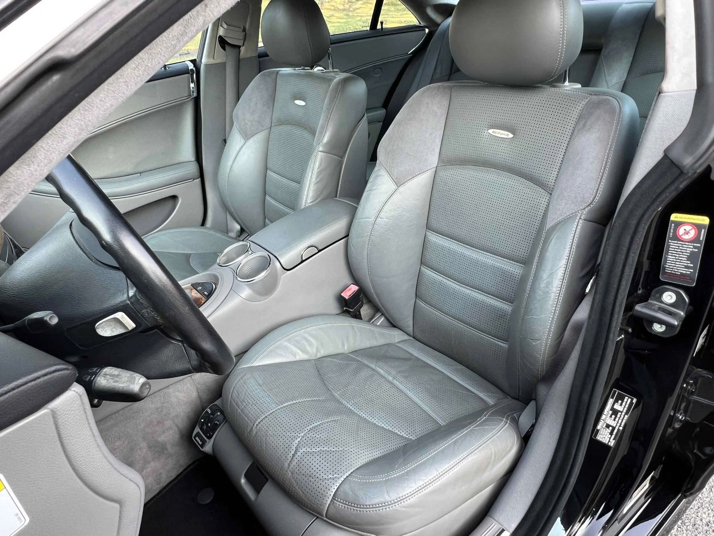 Interior of a car showing two front leather seats, a center console with two cup holders, and part of the dashboard.