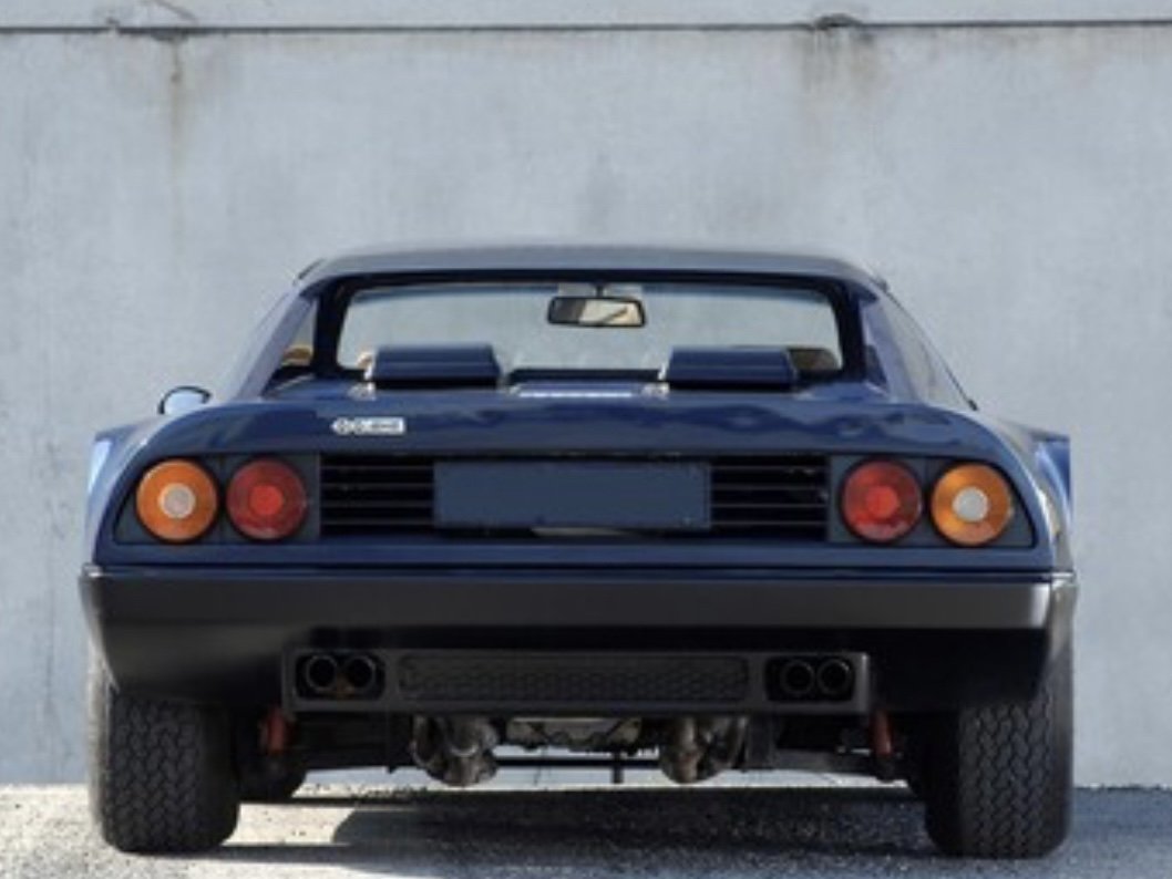 Rear of Blue 1979 Ferrari 512 BB on display in front of concrete wall