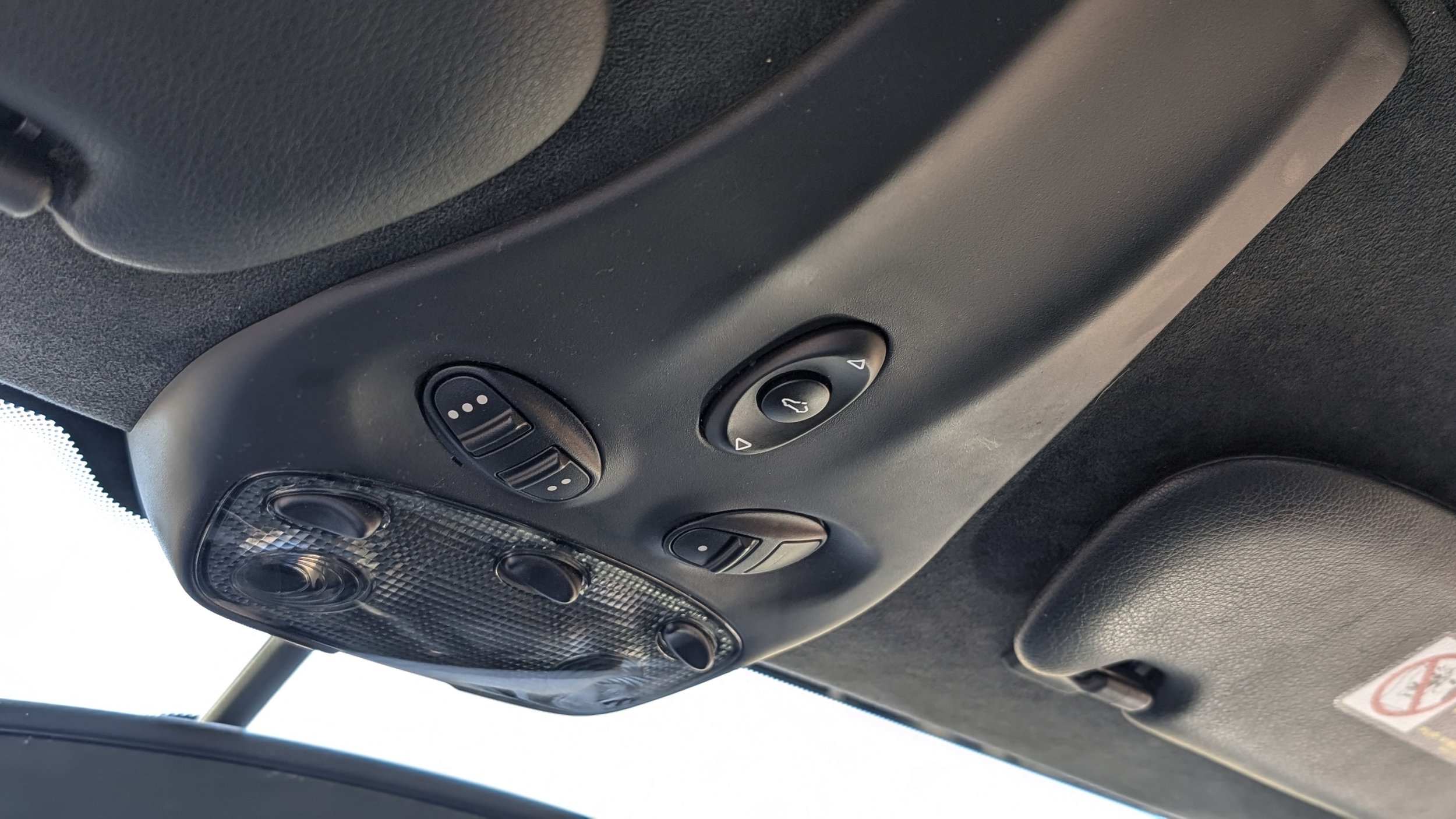 Ceiling controls in a vehicle, including lights and possibly climate or sunroof controls.