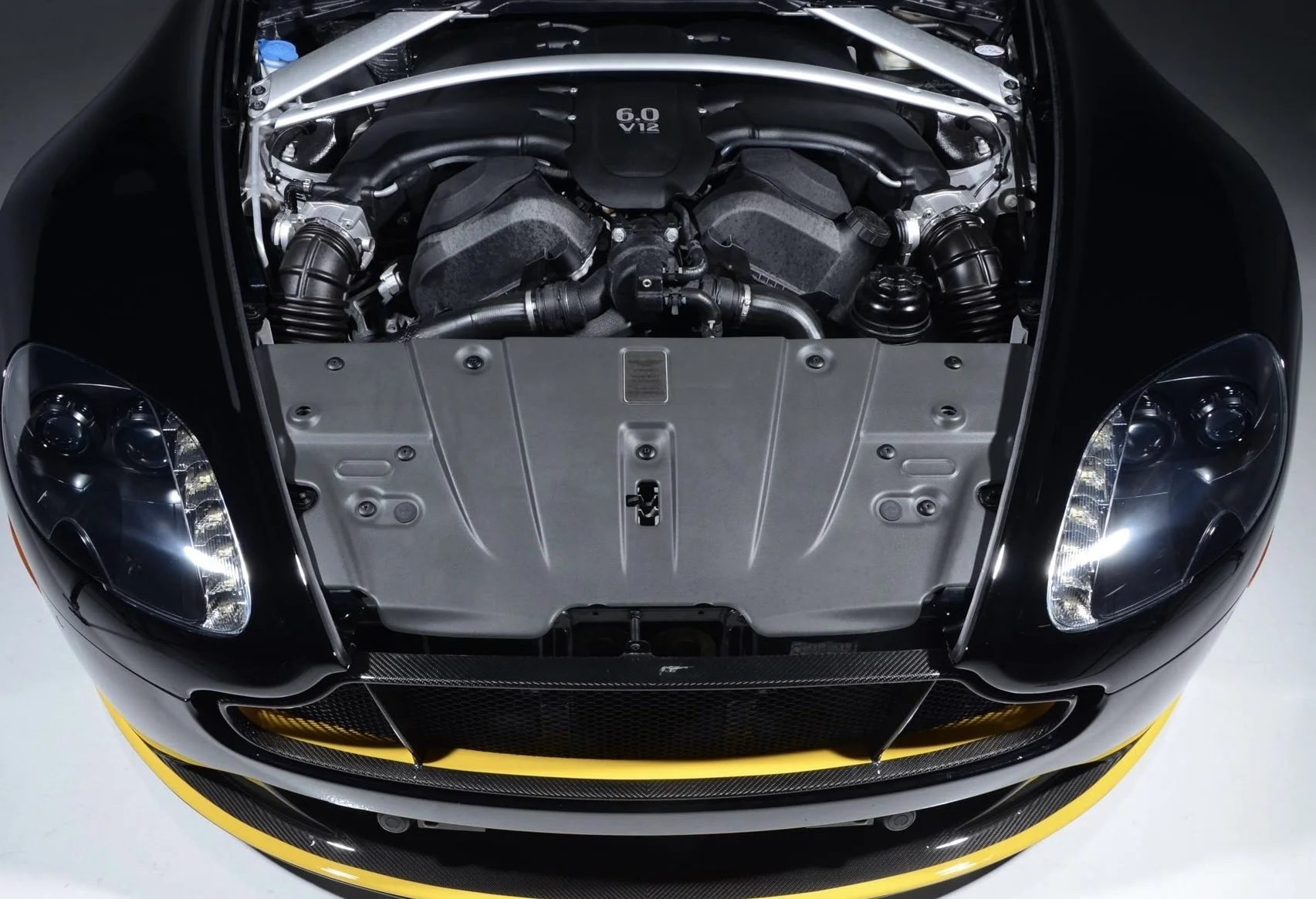 Front view of a sports car with the hood open, showing a V12 engine marked 6.0.