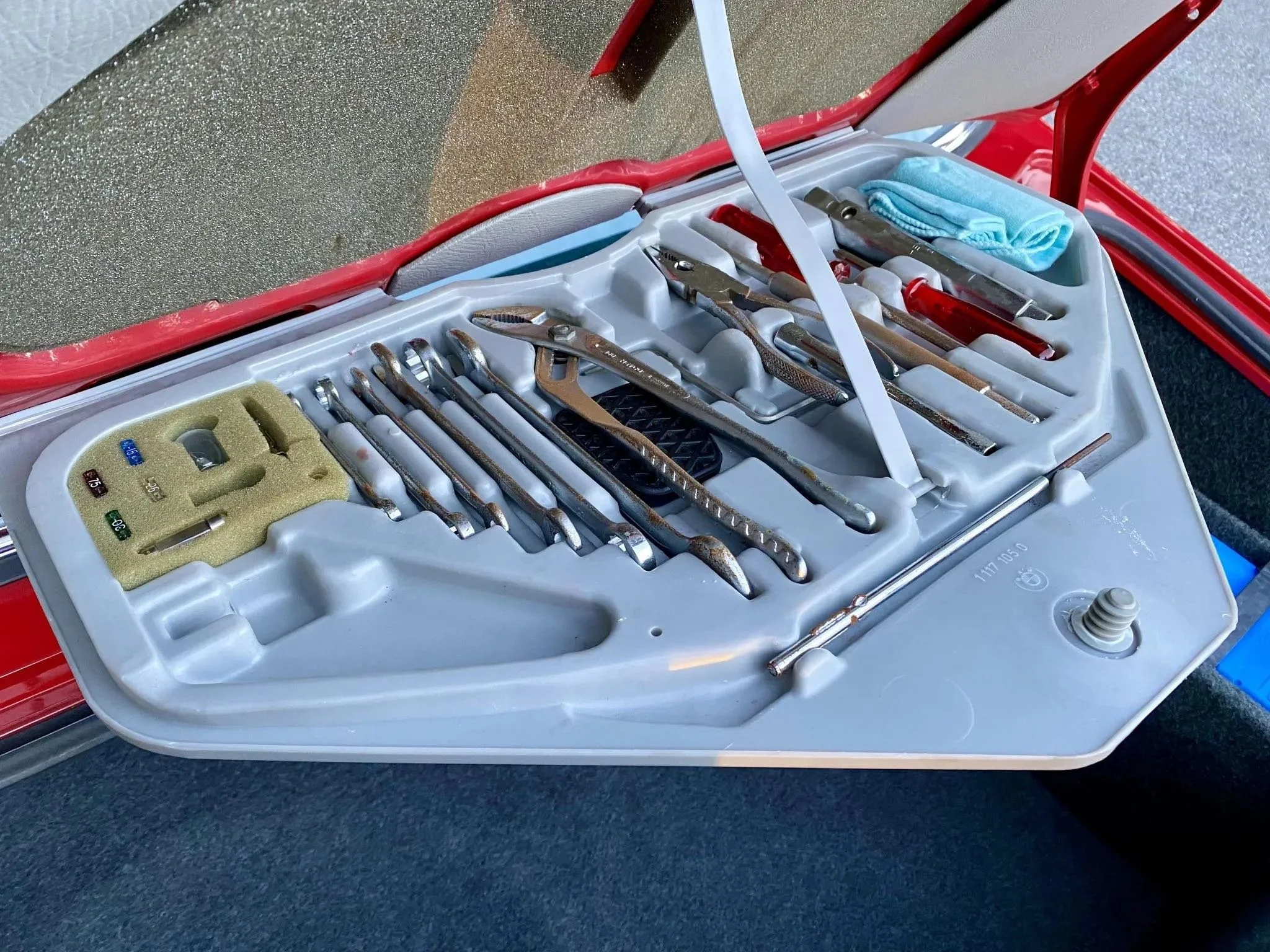 A collection of dental tools in a plastic case, including mirrors, scalers, and probes, with a blue cloth and cleaning supplies nearby.