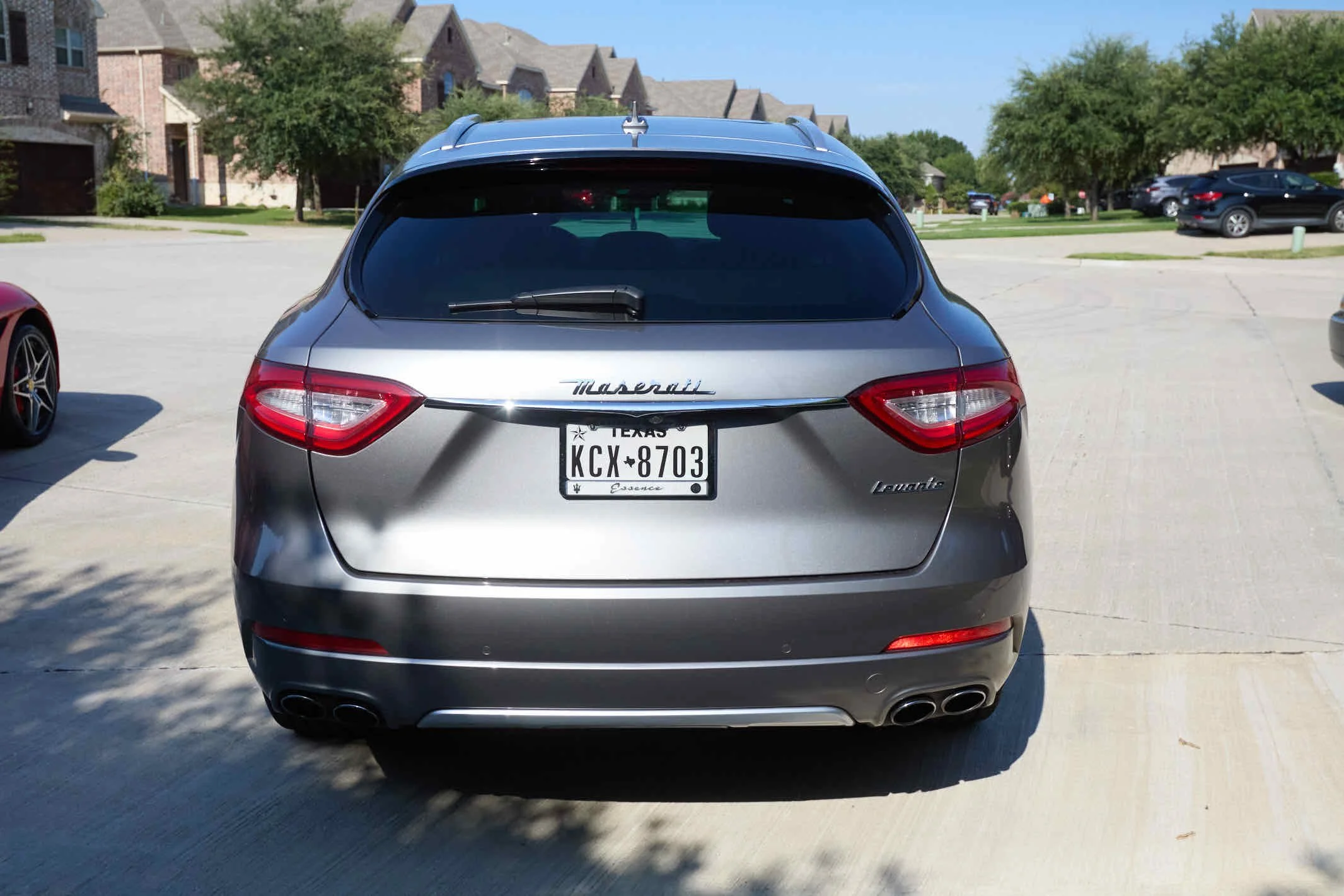 Rear view of a silver Maserati Levante SUV with Texas license plate KCX 8703 parked on a driveway in a suburban neighborhood.