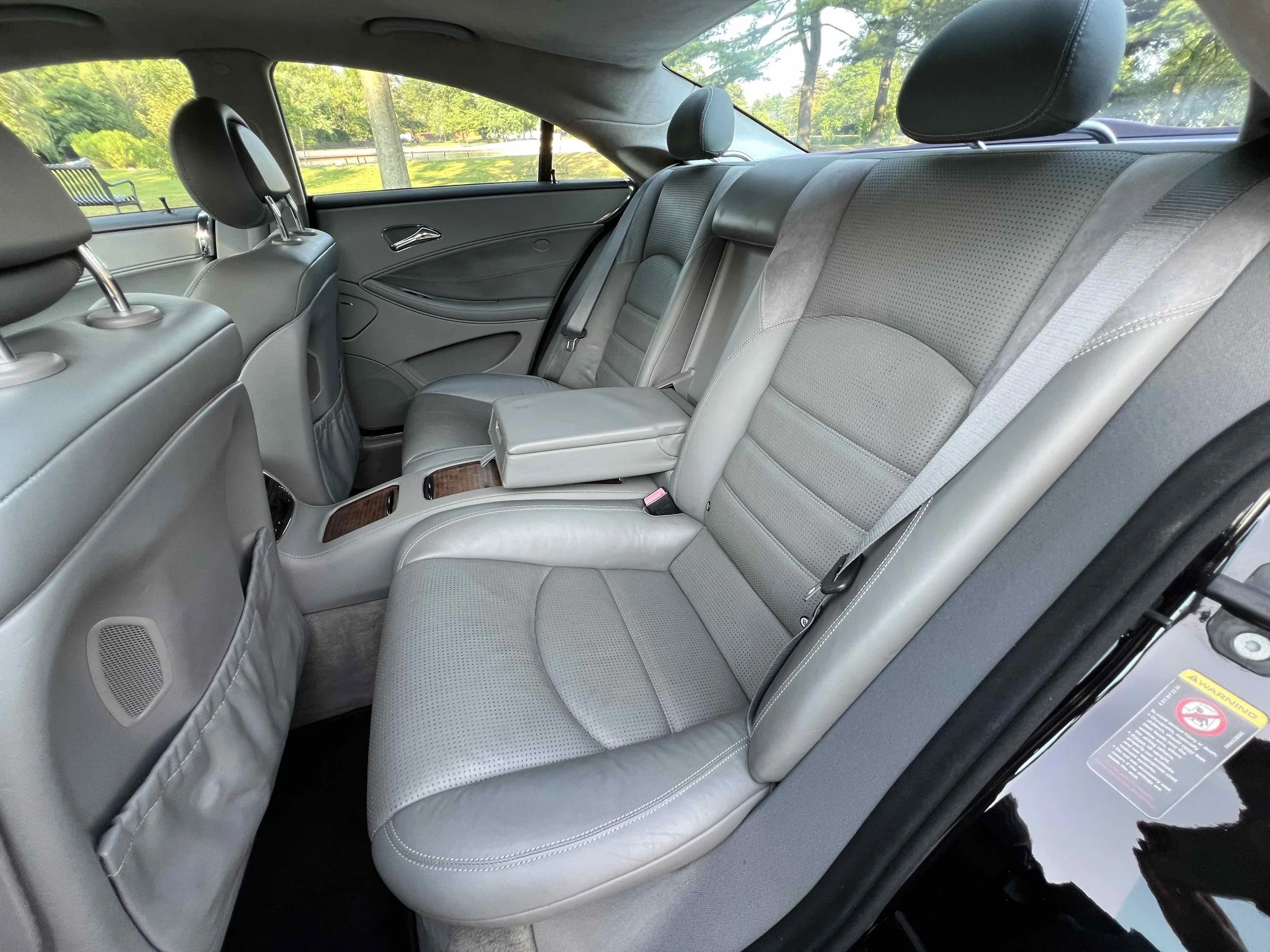 Interior of a luxury car with gray leather seats, rear passenger area, visible headrests, and wood trim accents.