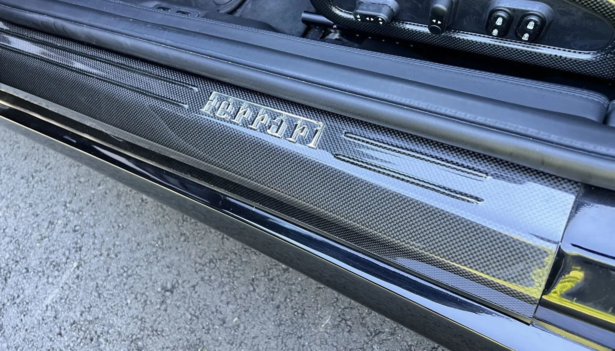A car door sill with a carbon fiber finish and a logo that says 'Lamborghini'.
