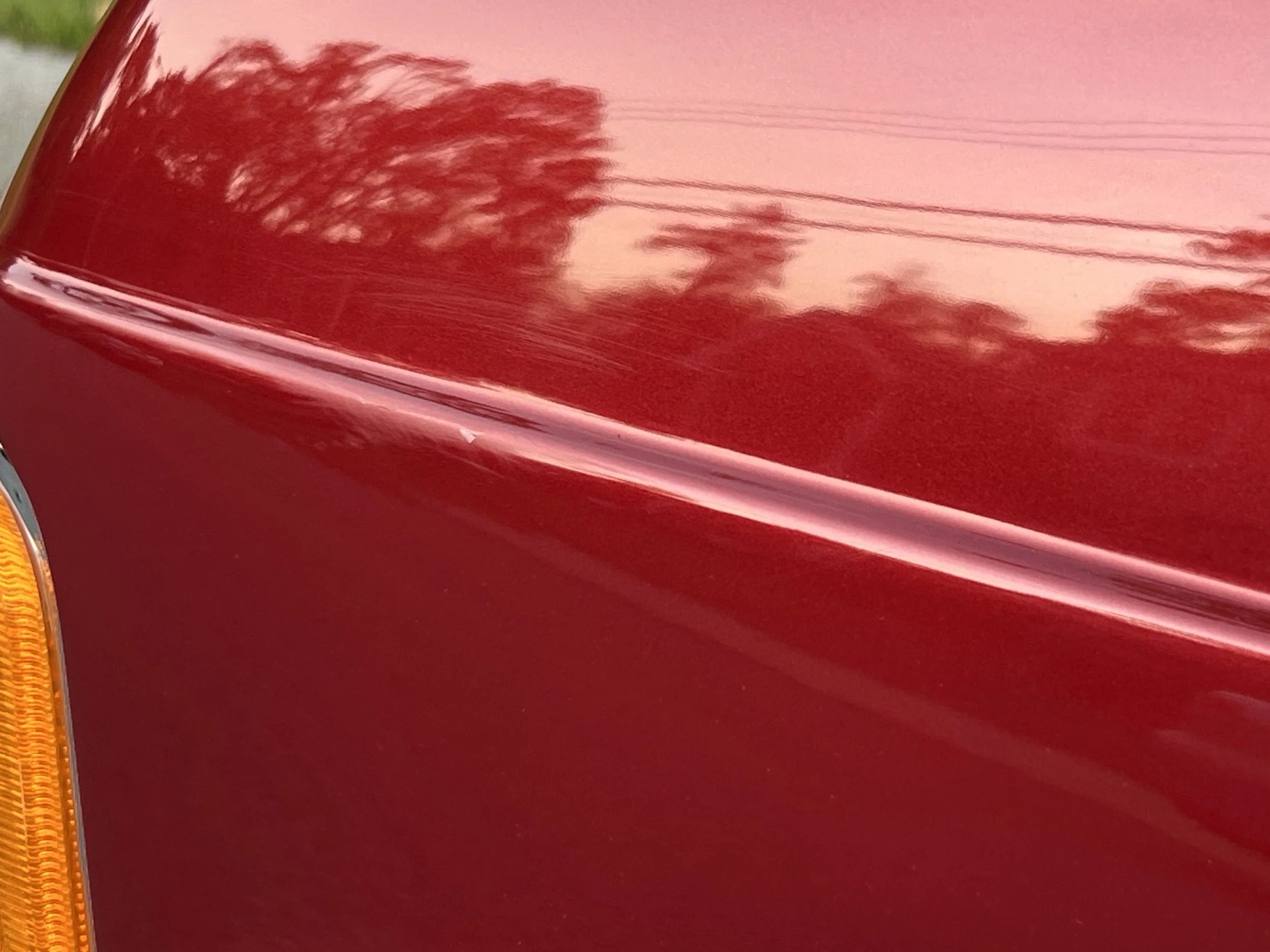 Close-up of a shiny red BMW 630 csi body with some reflections of trees and power lines.