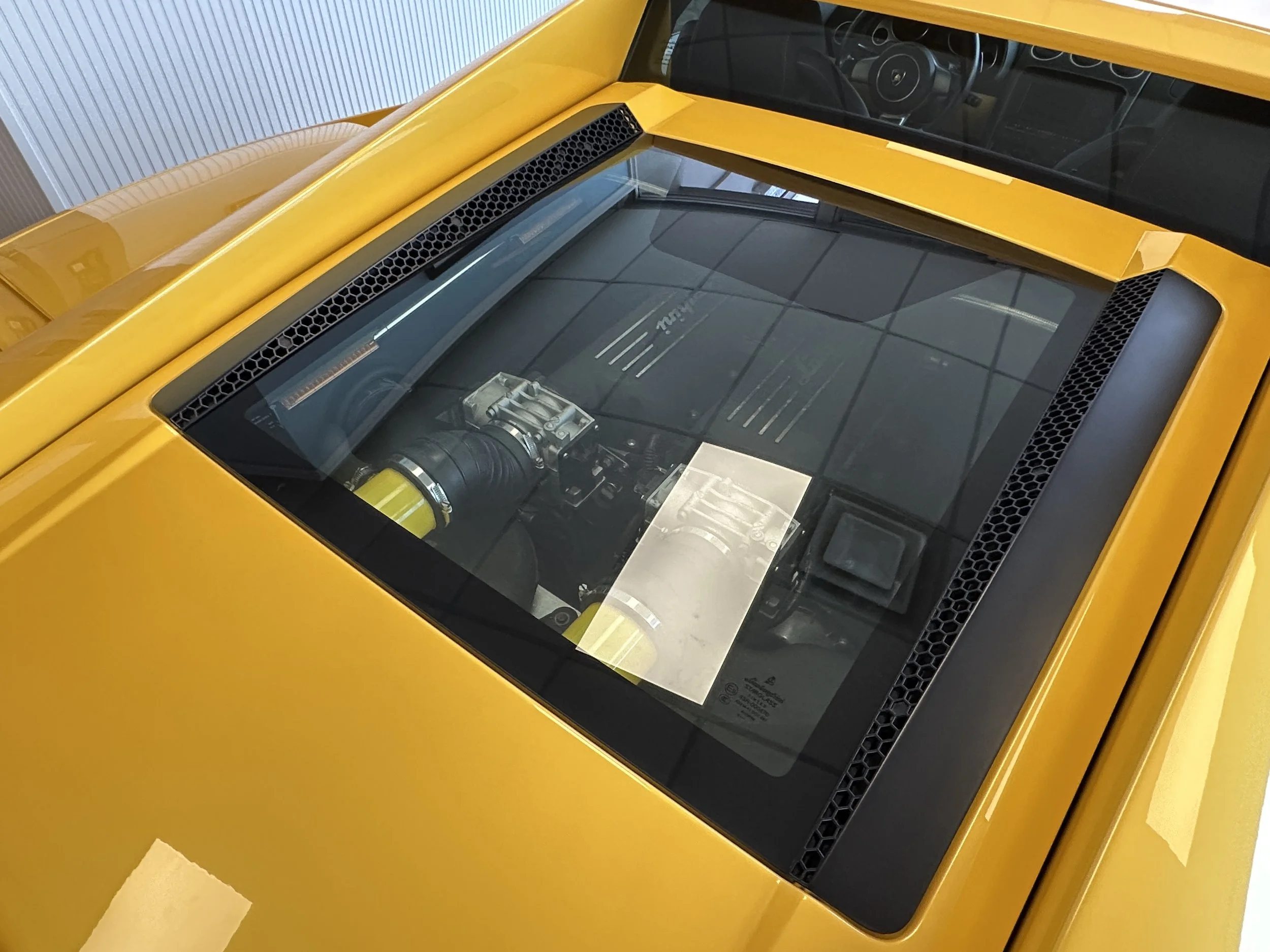 Top view of a yellow sports car with a clear engine cover showcasing the engine inside.