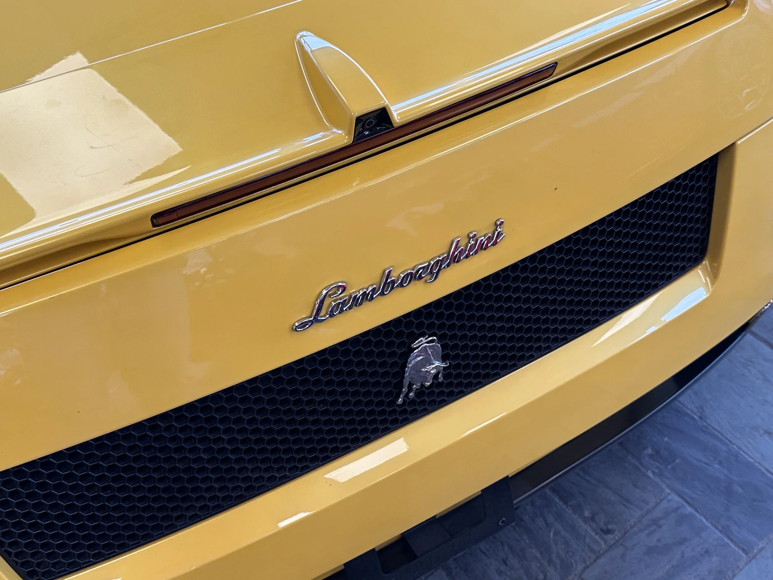 Close-up of the front of a yellow Lamborghini car, showing the Lamborghini badge and emblem.