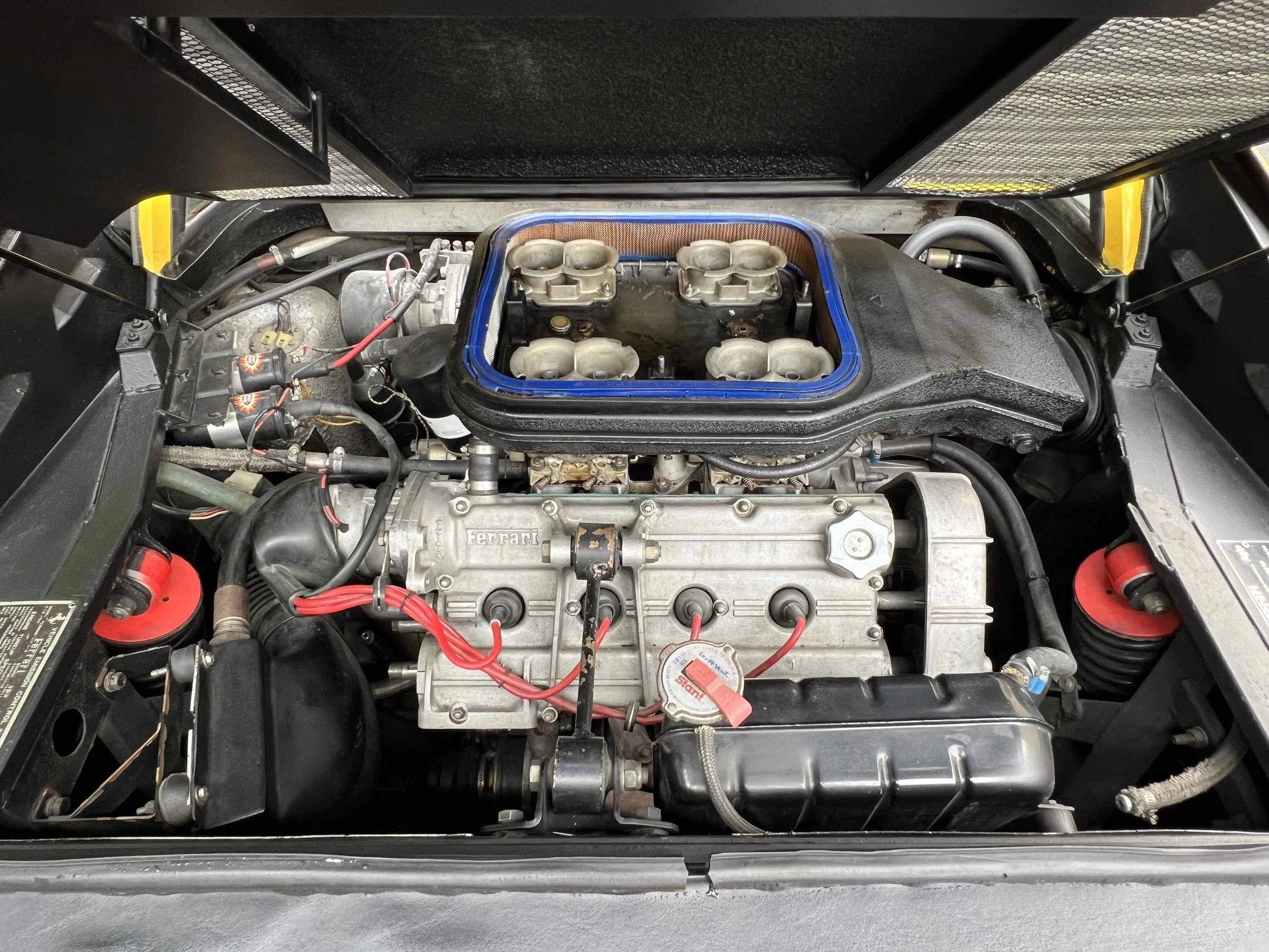 View of a Ferrari engine with visible components including intake manifold, wiring, and various engine parts.