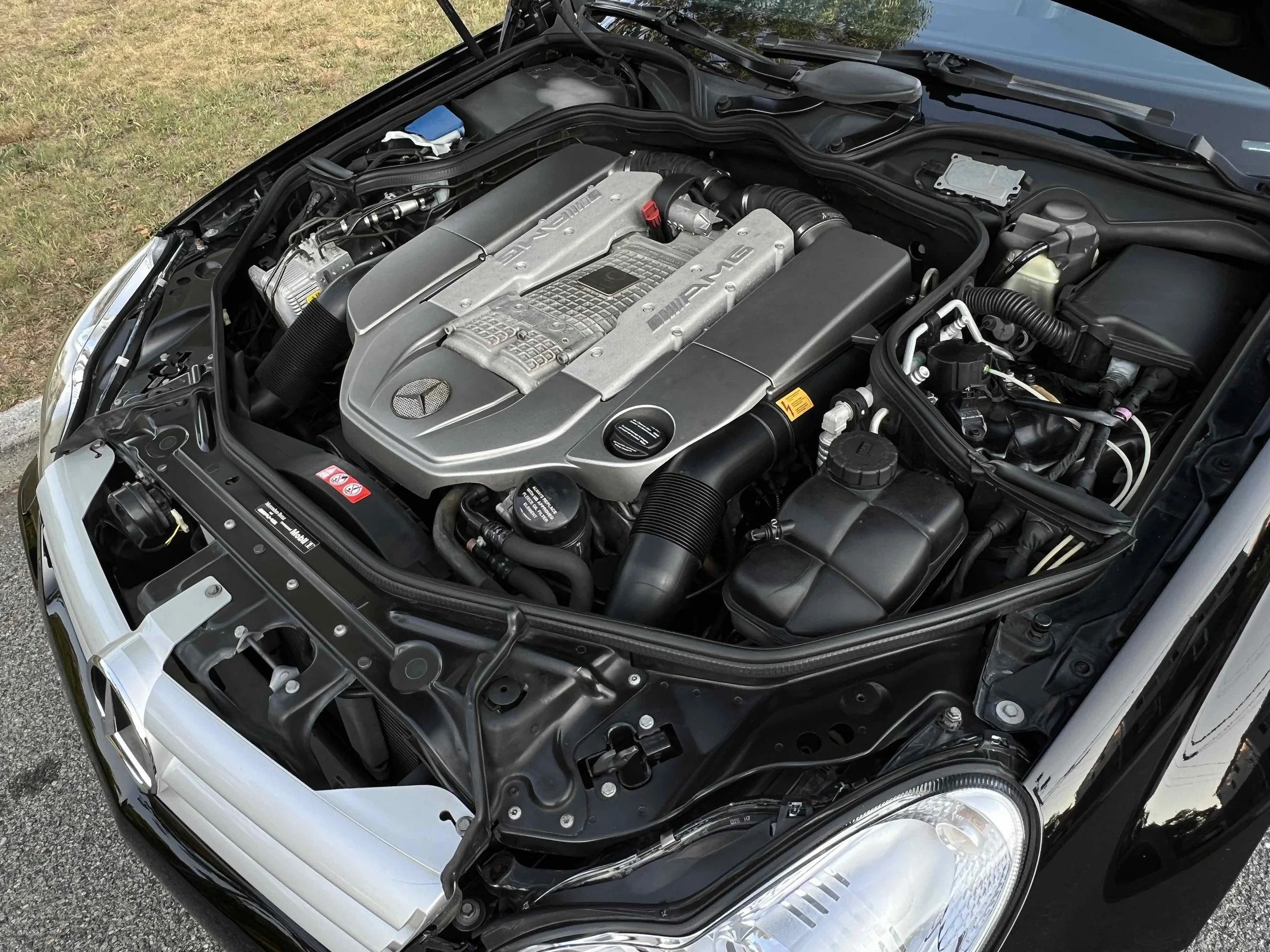 Close-up view of a Mercedes-Benz AMG engine in a car hood, showing various engine components.