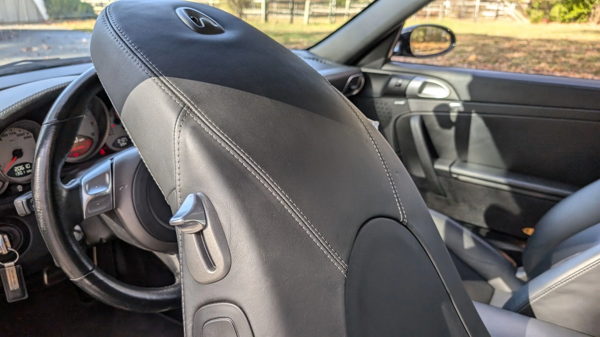 Interior of a car showing the front seats, dashboard with gauges, steering wheel, and a door with window.