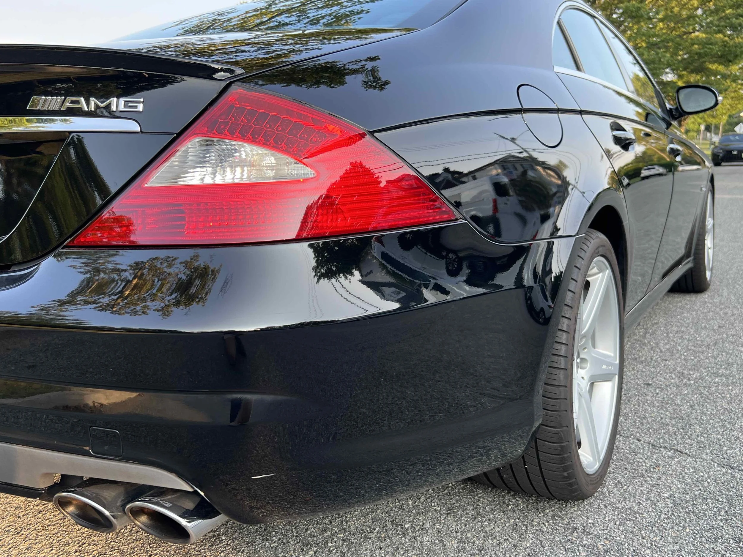 Black Mercedes-Benz CLS55 AMG  parked on a street with trees and houses in the background.