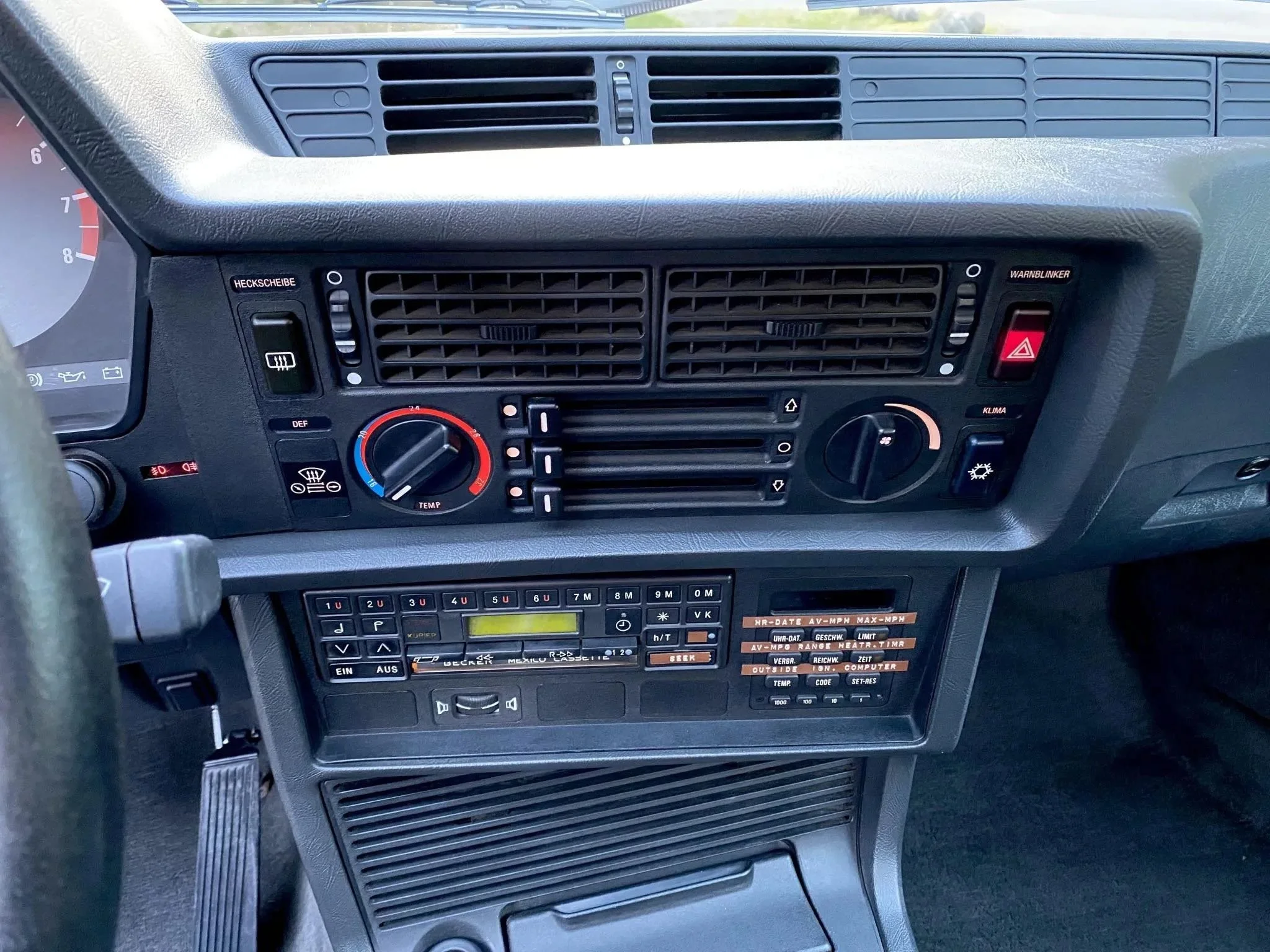Dashboard of a vehicle displaying air vents, climate controls, radio, and various buttons and switches.