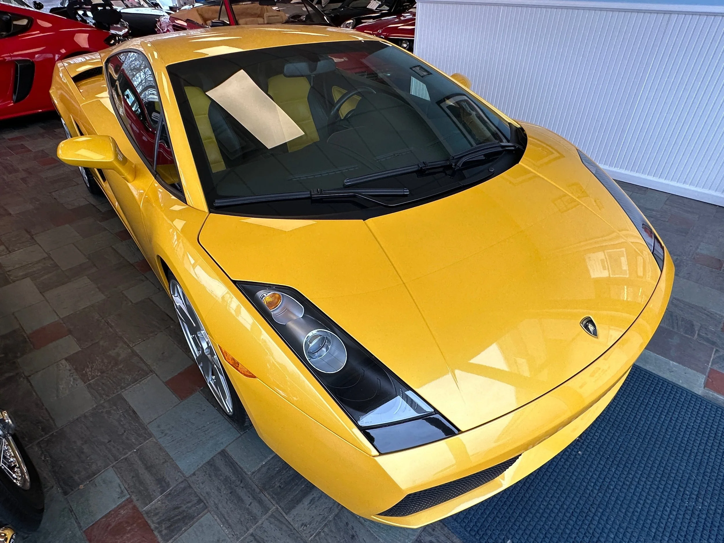 Yellow Lamborghini sports car parked in a lot with other cars nearby.