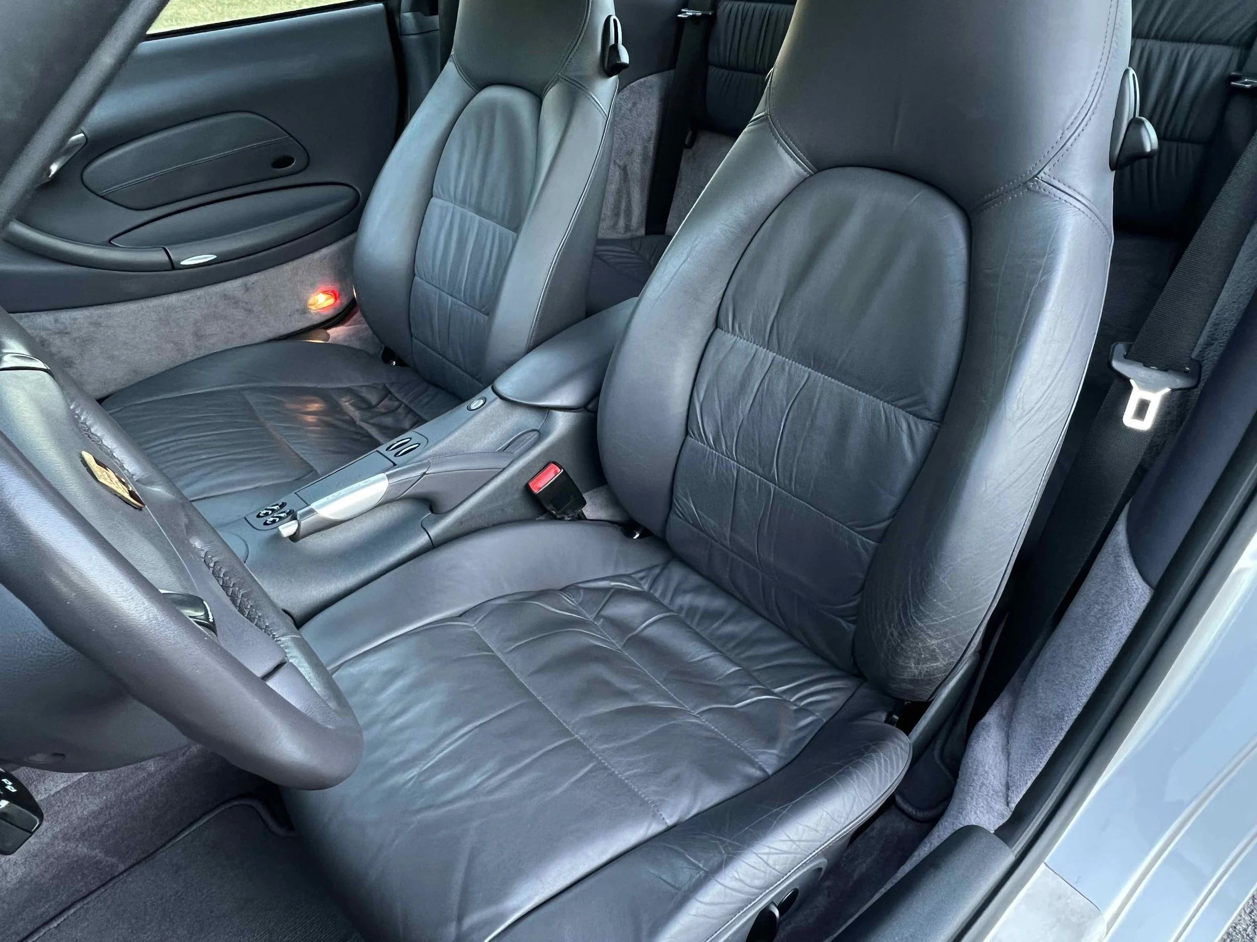 Close-up view of the front leather seats and part of the dashboard of a car interior.
