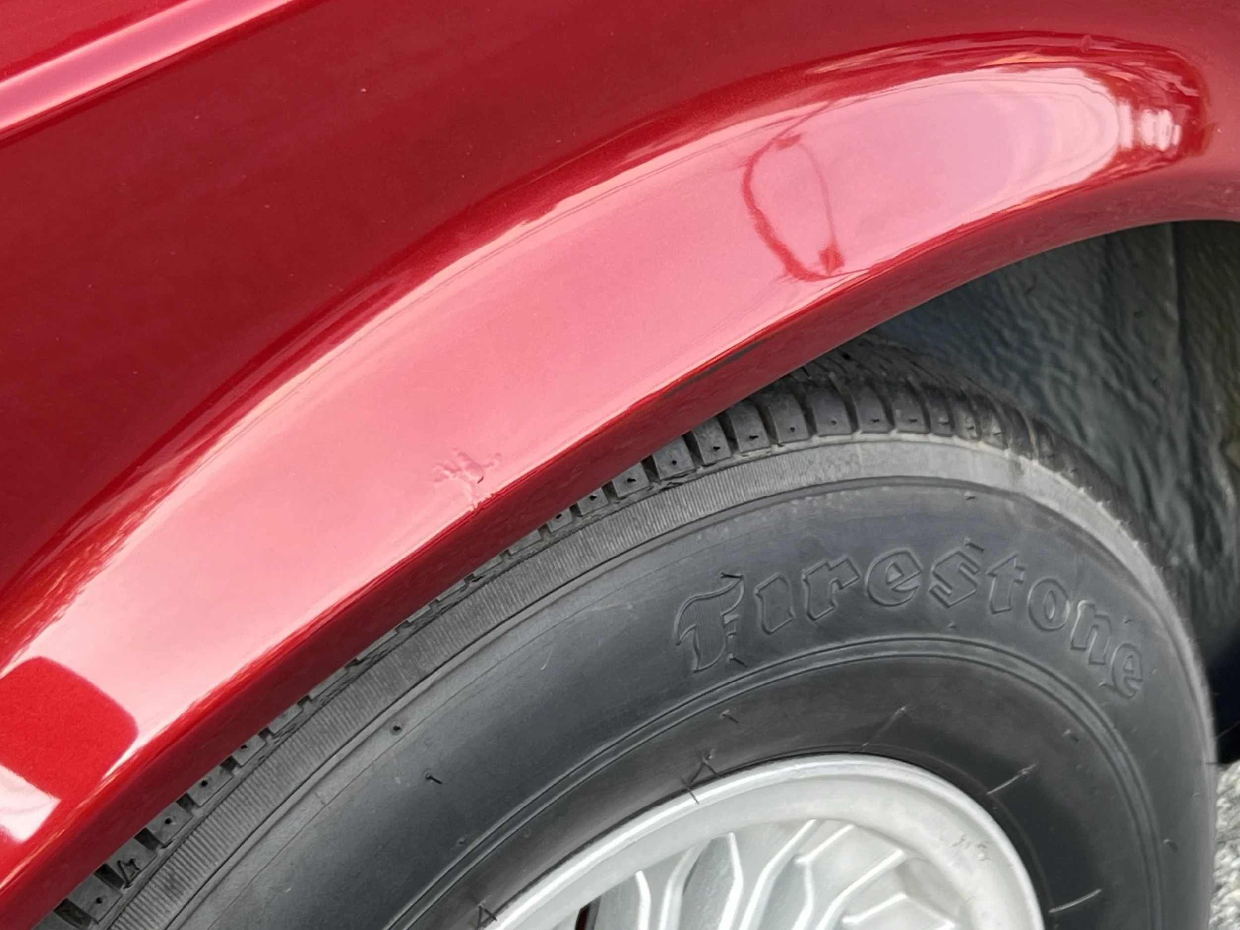 Close-up of a red BMW 630 csi fender and tire, with the tire branding 'Firestone' visible.
