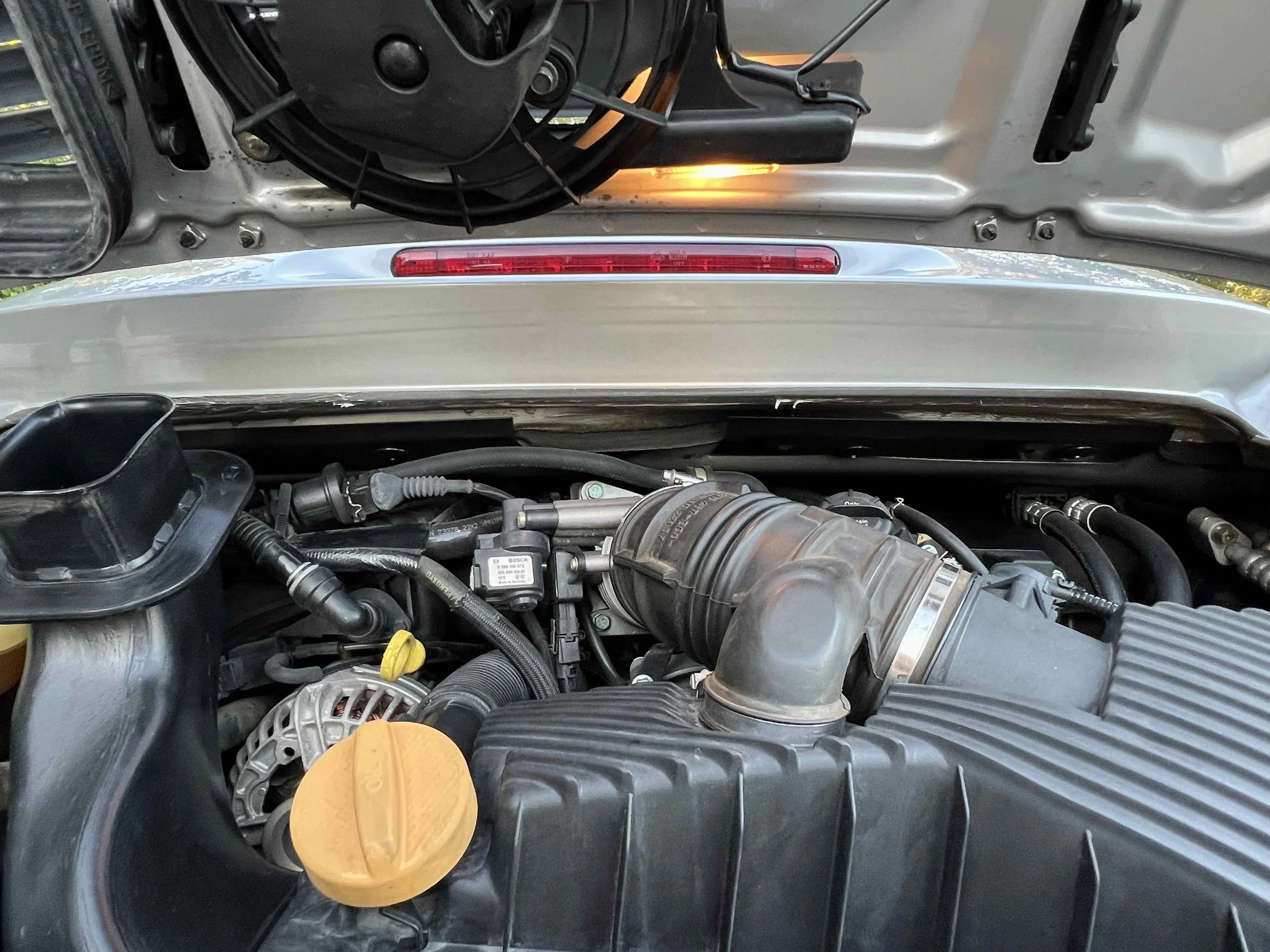 Car engine with visible air intake, dipstick, and various hoses and components.