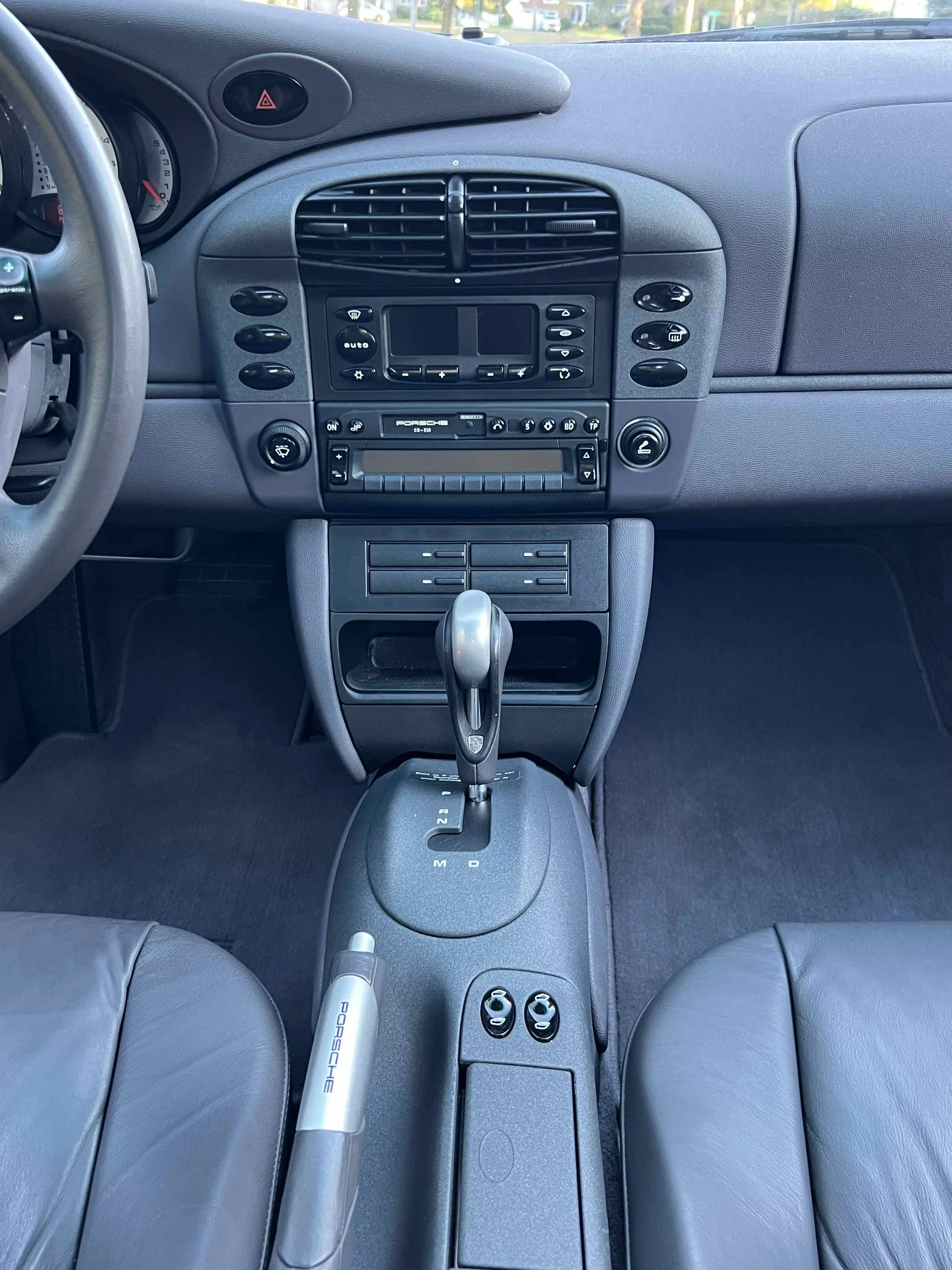 Interior of a Porsche sports car, showing the dashboard, gear shift, and center console with controls and a navigation screen.