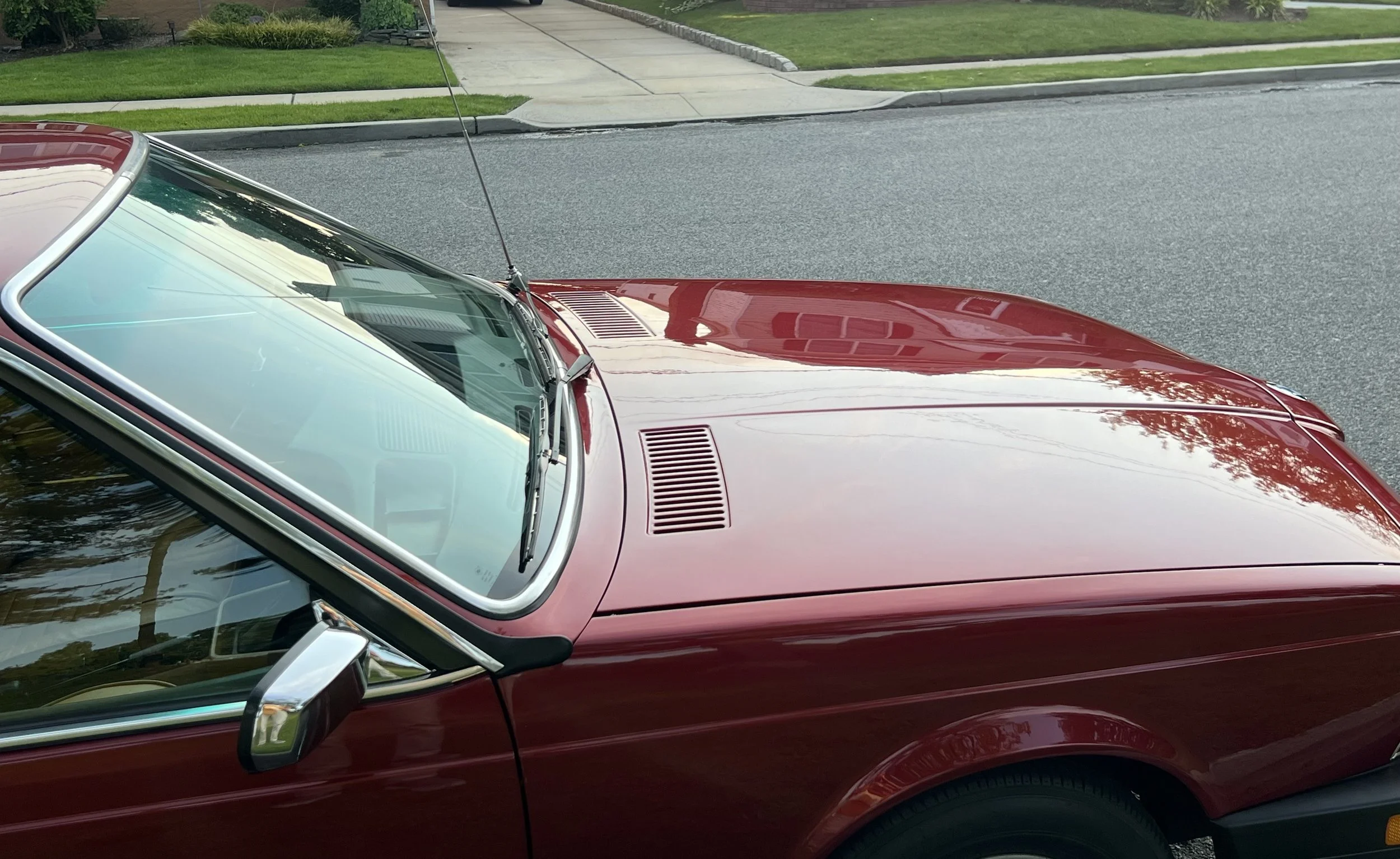 Front of Ruby Red 1977 BMW 630 csi on display in park for sale at FlowHaus