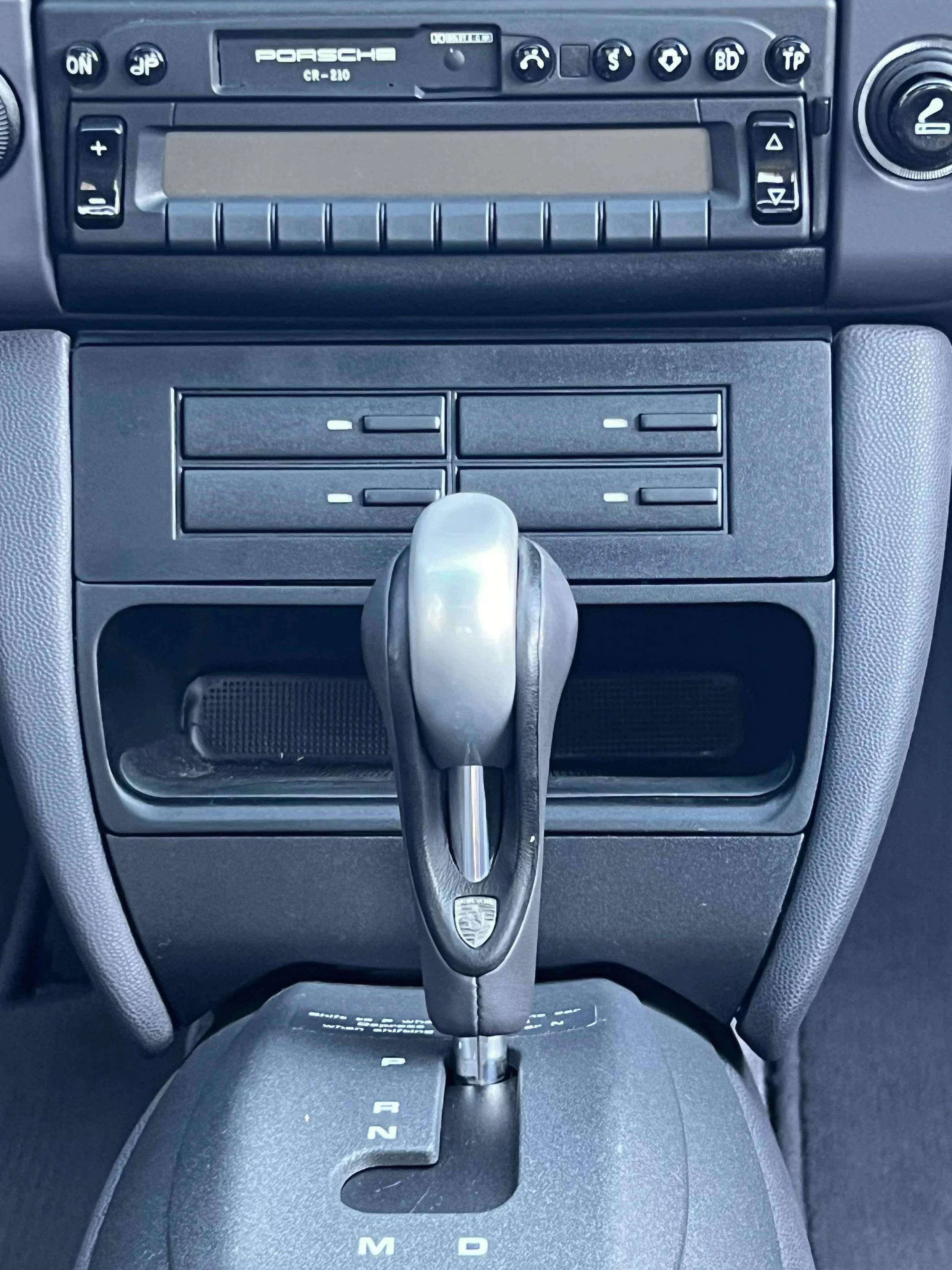 Interior of a Porsche car showing the gear shift lever and dashboard controls.